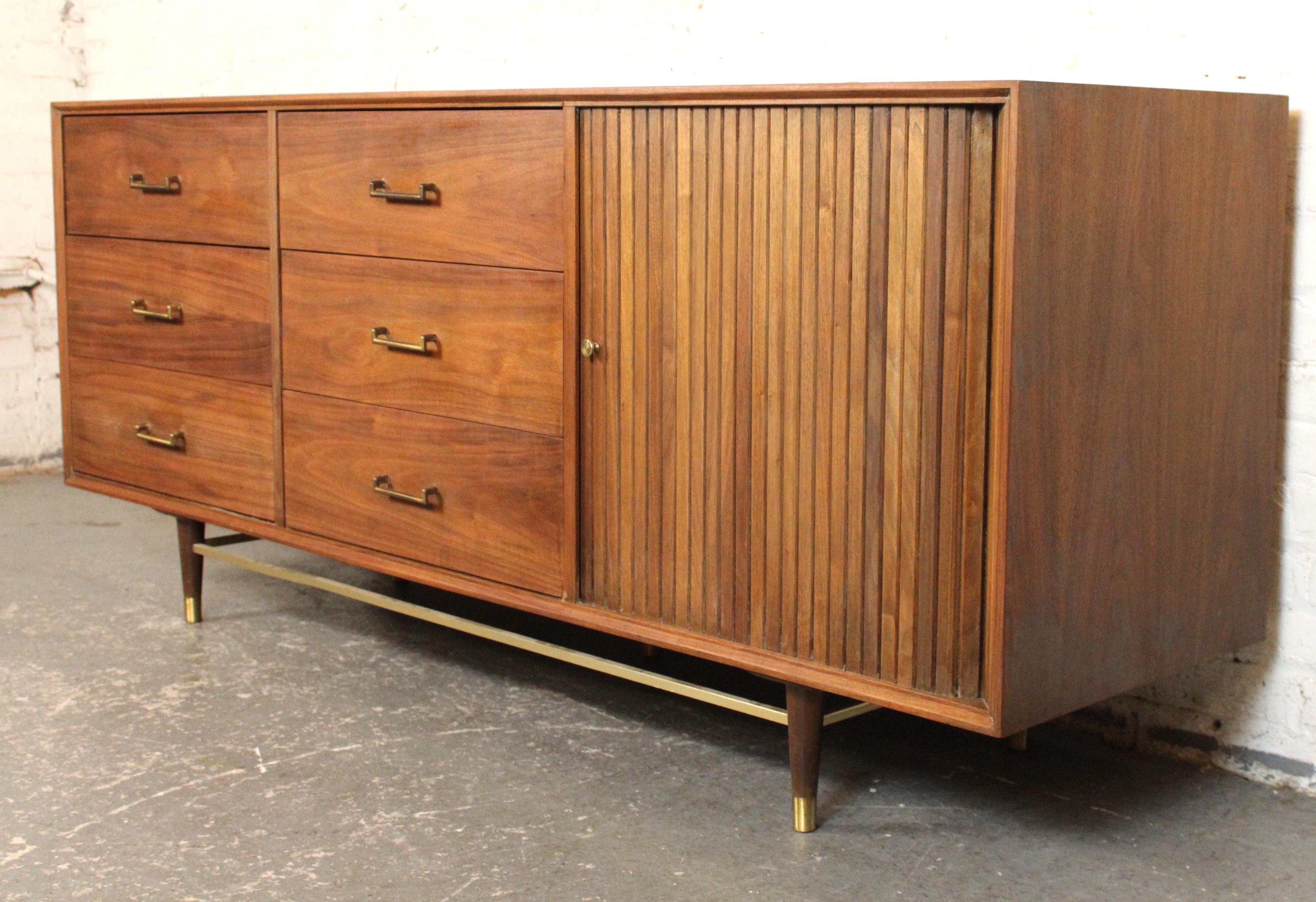 Comò americano della metà del secolo scorso realizzato da Furnette. Presenta una calda venatura di noce e una ferramenta in ottone. Sei cassetti a vista più una serie di cassetti nascosti dietro un'anta tamburata.
Si prega di confermare l'ubicazione