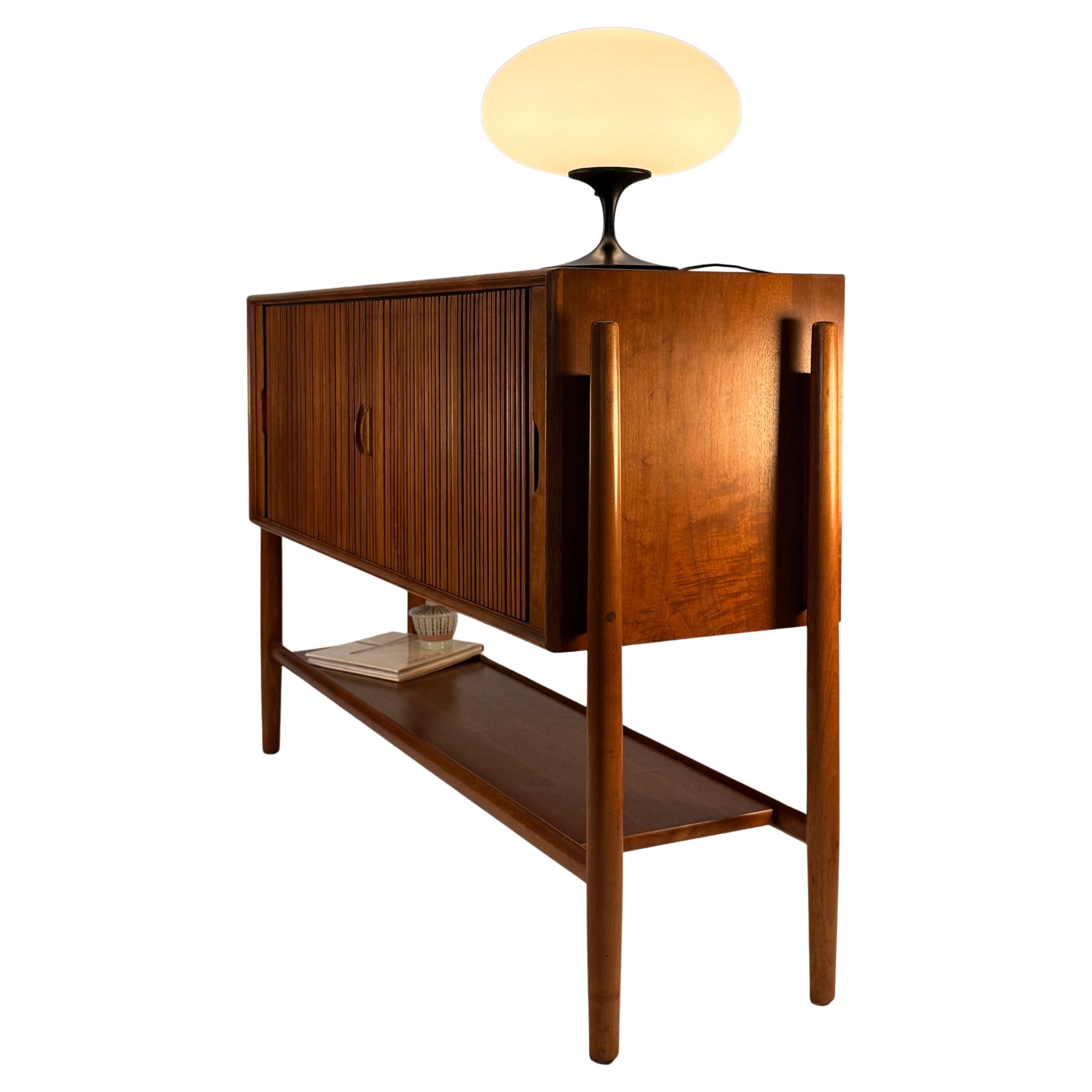 This is a rare and exceptional Mid-Century Modern walnut tambour door sideboard or credenza designed by Barney Flagg for the Parallel line by Drexel. We live this piece because it has such charm and a great profile. The credenza features gorgeous