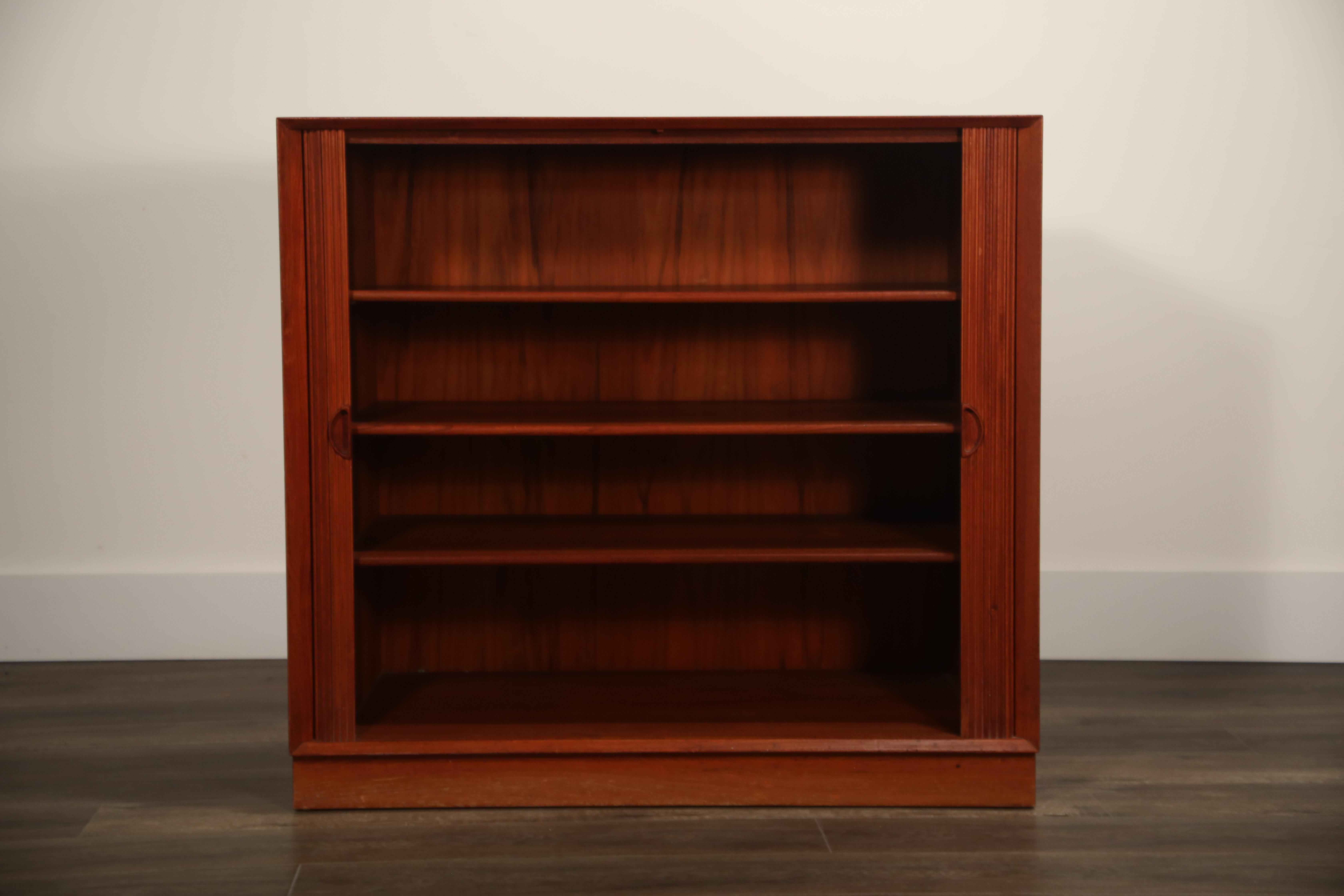 A lovely Danish modern teak cabinet with tambour front doors by Peter Hvidt & Orla Mølgaard Nielsen for Illums Bolighus. This charming chest features three interior adjustable shelves, high quality joinery and incredible teak grain and color. In