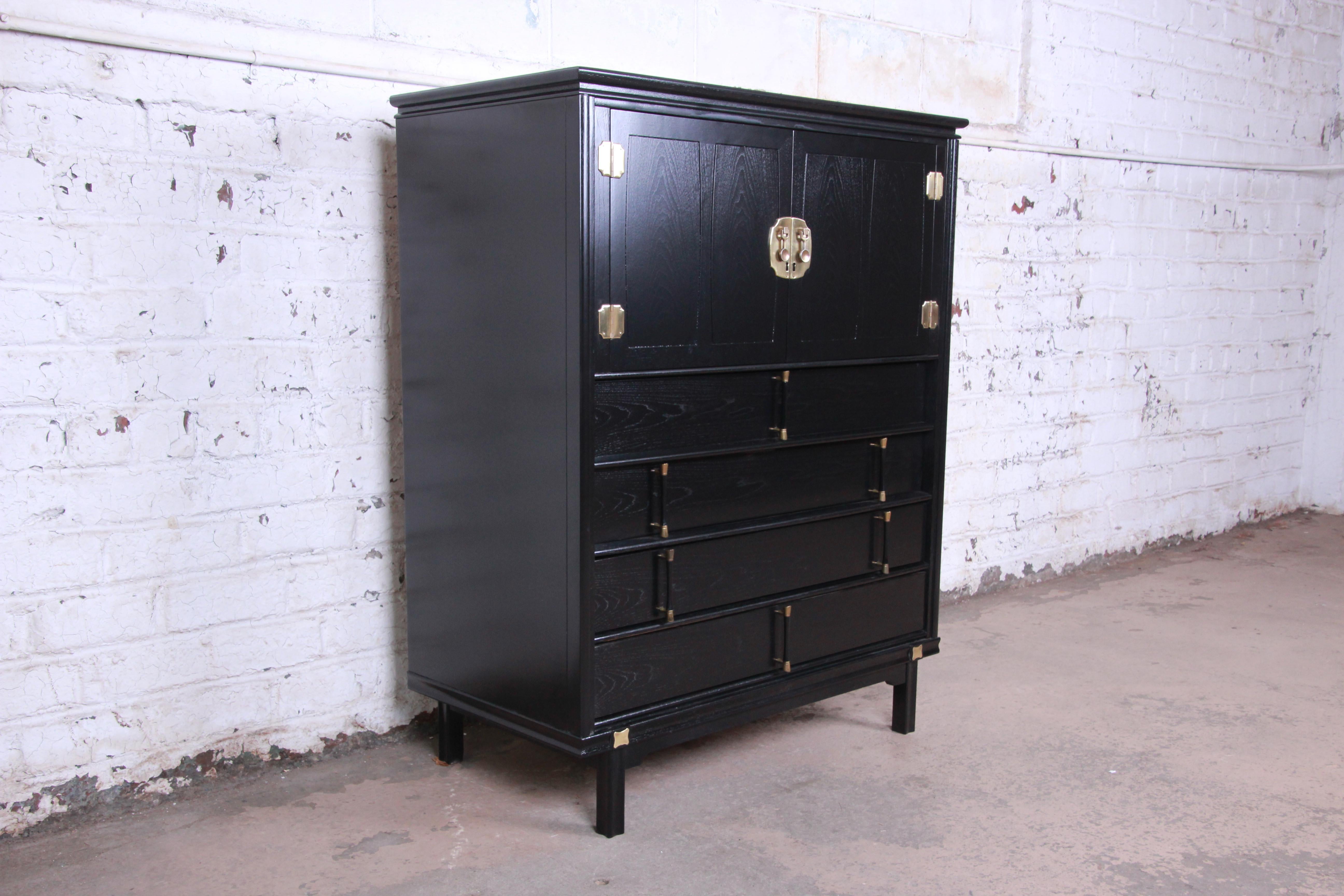 An exceptional Hollywood Regency chinoiserie gentleman's chest from the Tamerlane collection by Thomasville. The dresser features gorgeous walnut wood grain with a newly ebonized finish and brass hardware and accents. It offers ample storage, with