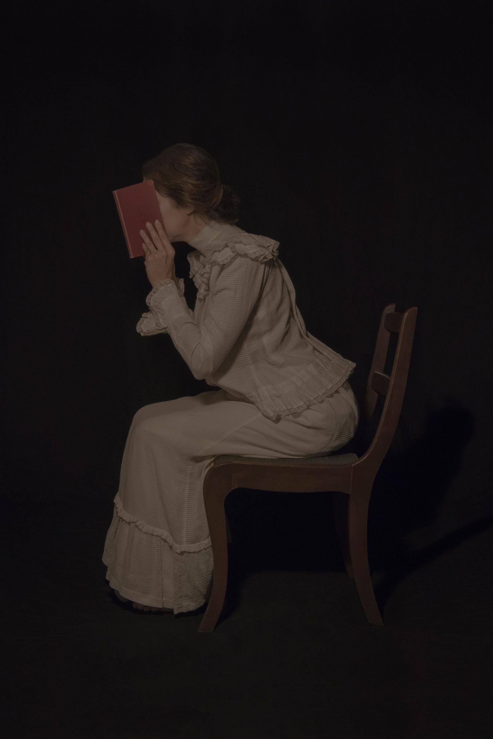 Tami Bahat Figurative Photograph - The Intellectual - Photography of a Girl Reading a book in a Dress, Moody, Dark