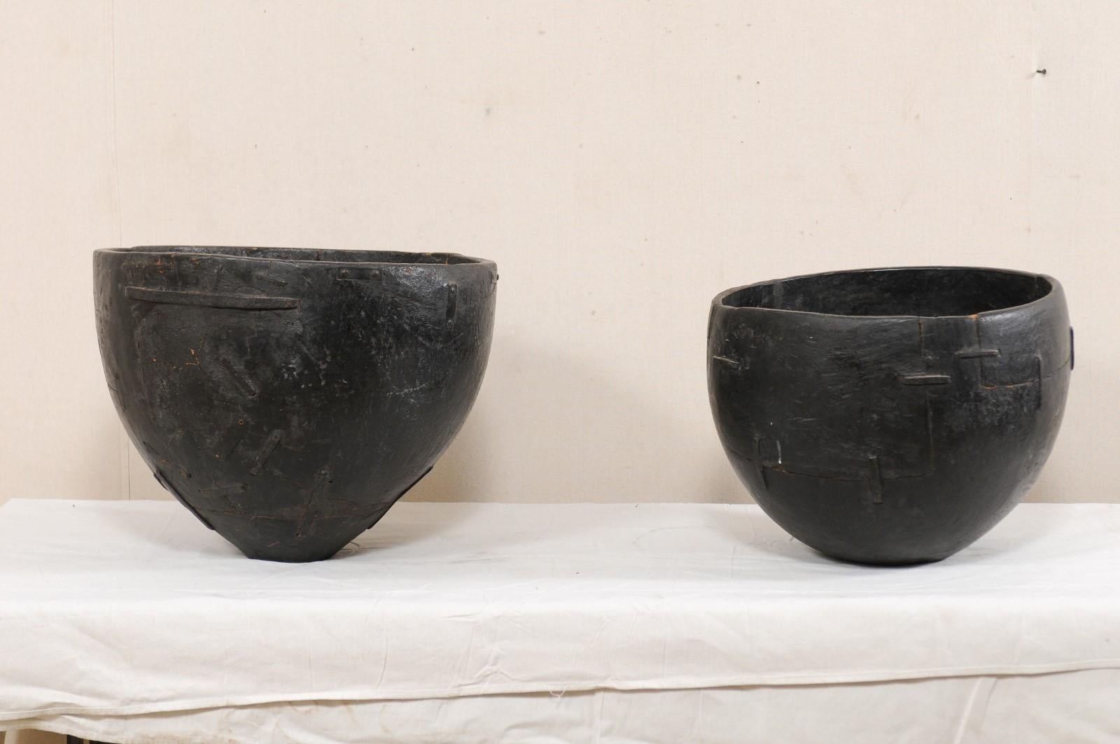 A pair of wooden water vessels with lovely old repairs from the early 20th century, Tamil Nadu, South India. This pair of antique wooden buckets from South India, originally used as water dippers, have been hand carved from a single piece of wood,