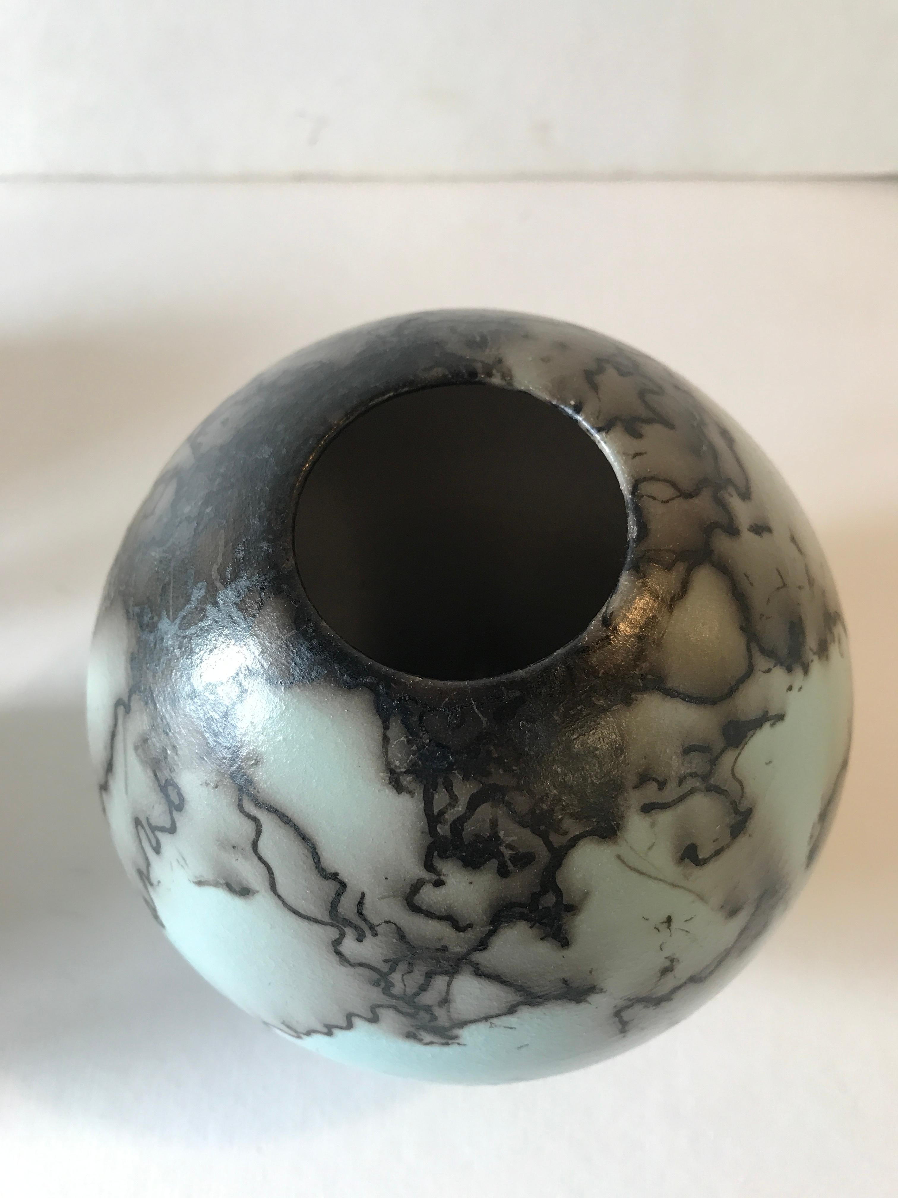 Duck Egg Blue Horse Hair Raku Fired Ball Vase by Tamsin Levene.

ADDITIONAL INFORMATION:
Duck Egg blue horse hair raku fired ball vase by Tamsin Levene
Ceramic on Stone
16 H x 15 W x 15 D cm (7.87 x 5.91 x 5.91 in)

SIZES:
Large: 16 cm x 15