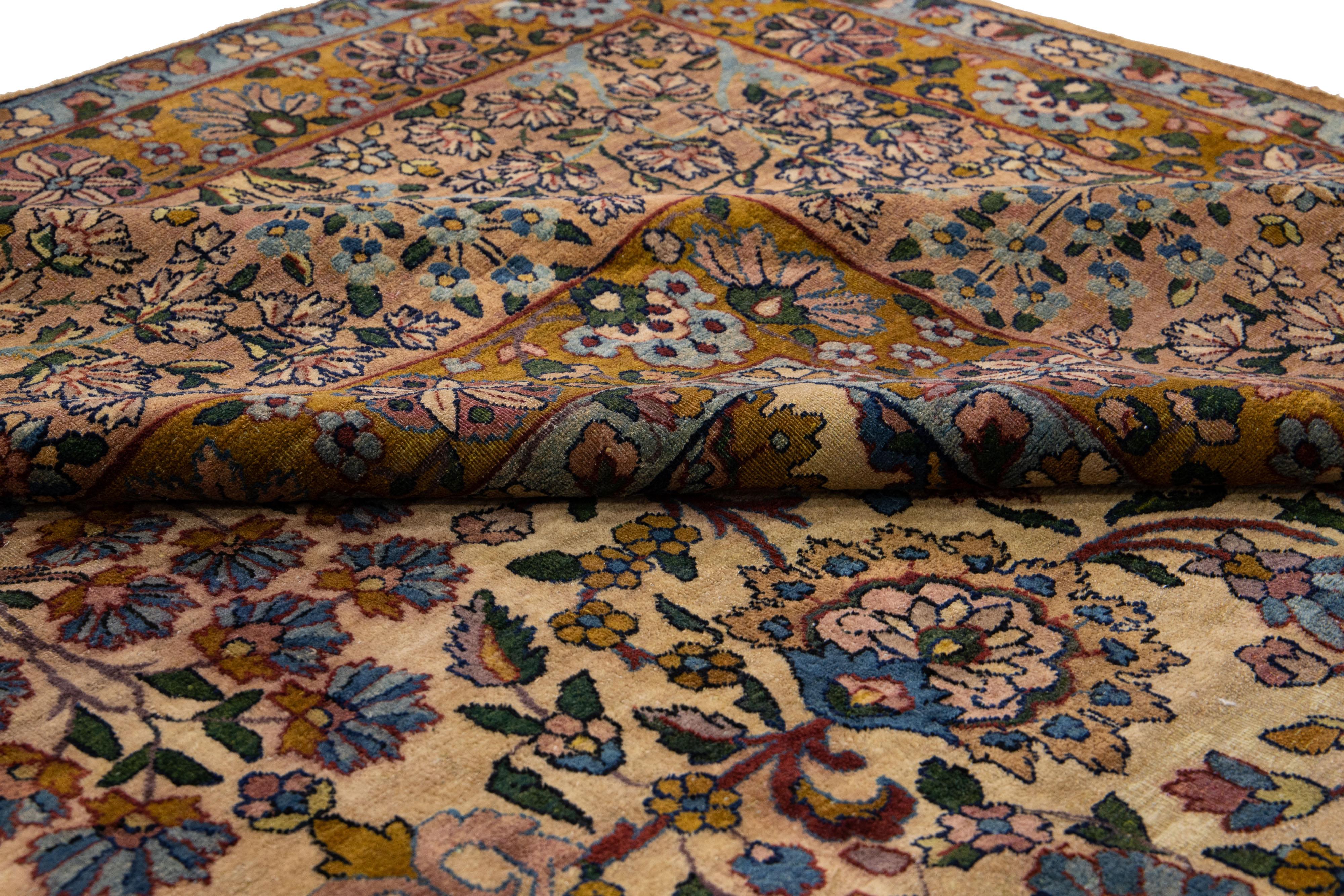 Beautiful antique Kerman hand-knotted wool rug with a tan field. This Persian rug has a brown frame with multicolor accents in a gorgeous all-over floral pattern design.

This rug measures: 12'9