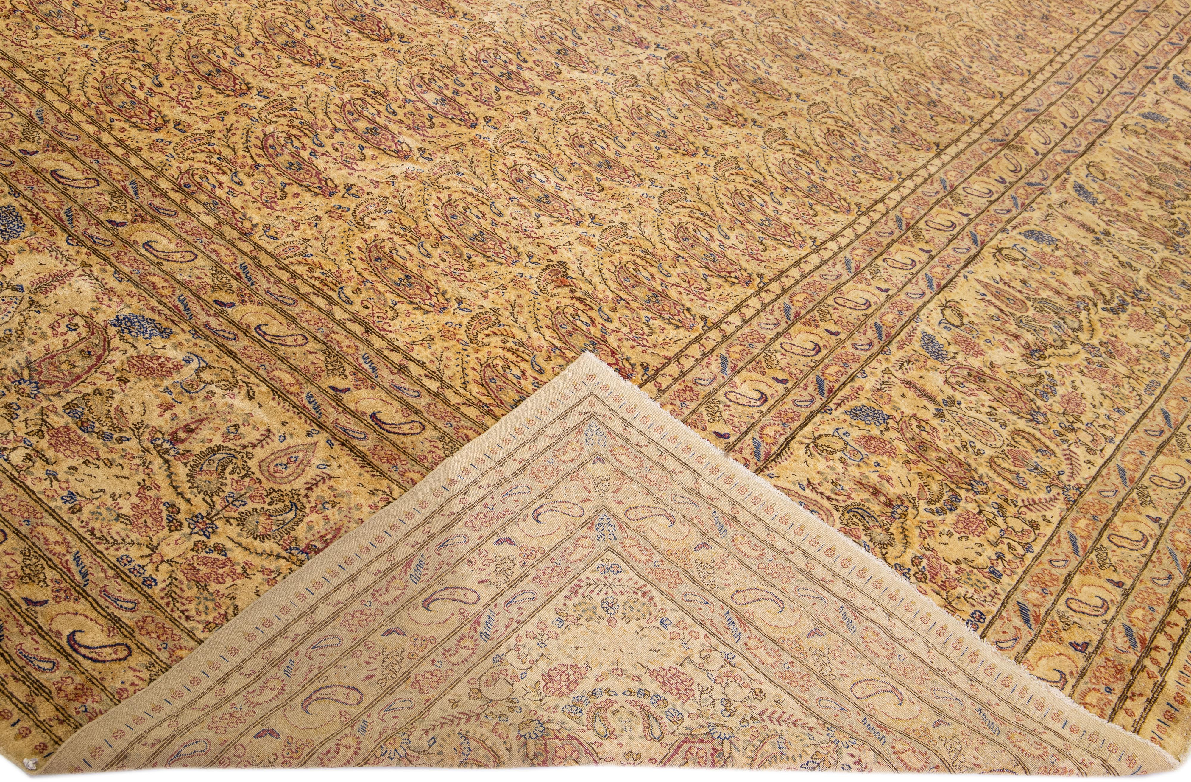 Beautiful antique Kerman hand-knotted wool rug with a tan field. This Persian rug has multicolor accents in a gorgeous all-over floral pattern design.

This rug measures: 16' x 20'8