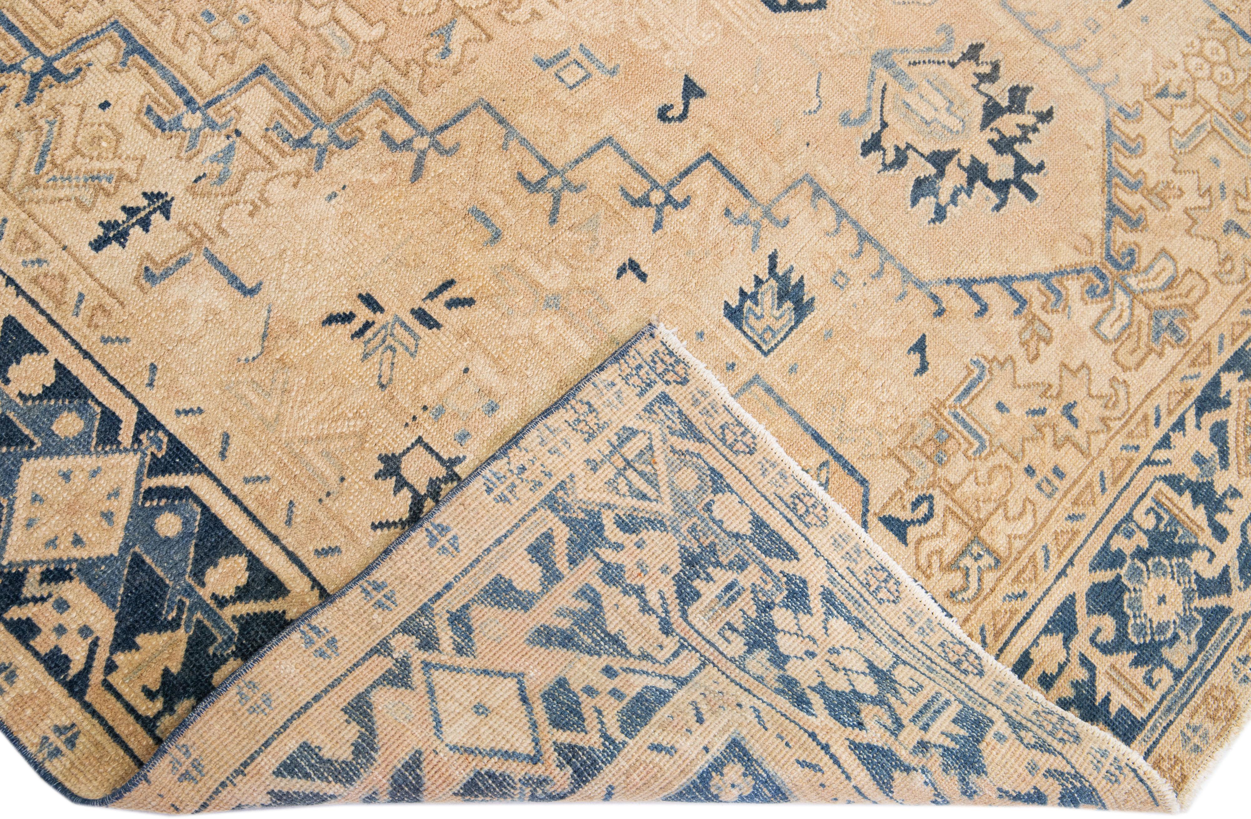 Beautiful antique Heriz hand-knotted wool rug with a tan color field. This Persian rug has a blue frame and accents in a gorgeous all-over medallion design.

This rug measures: 7'3