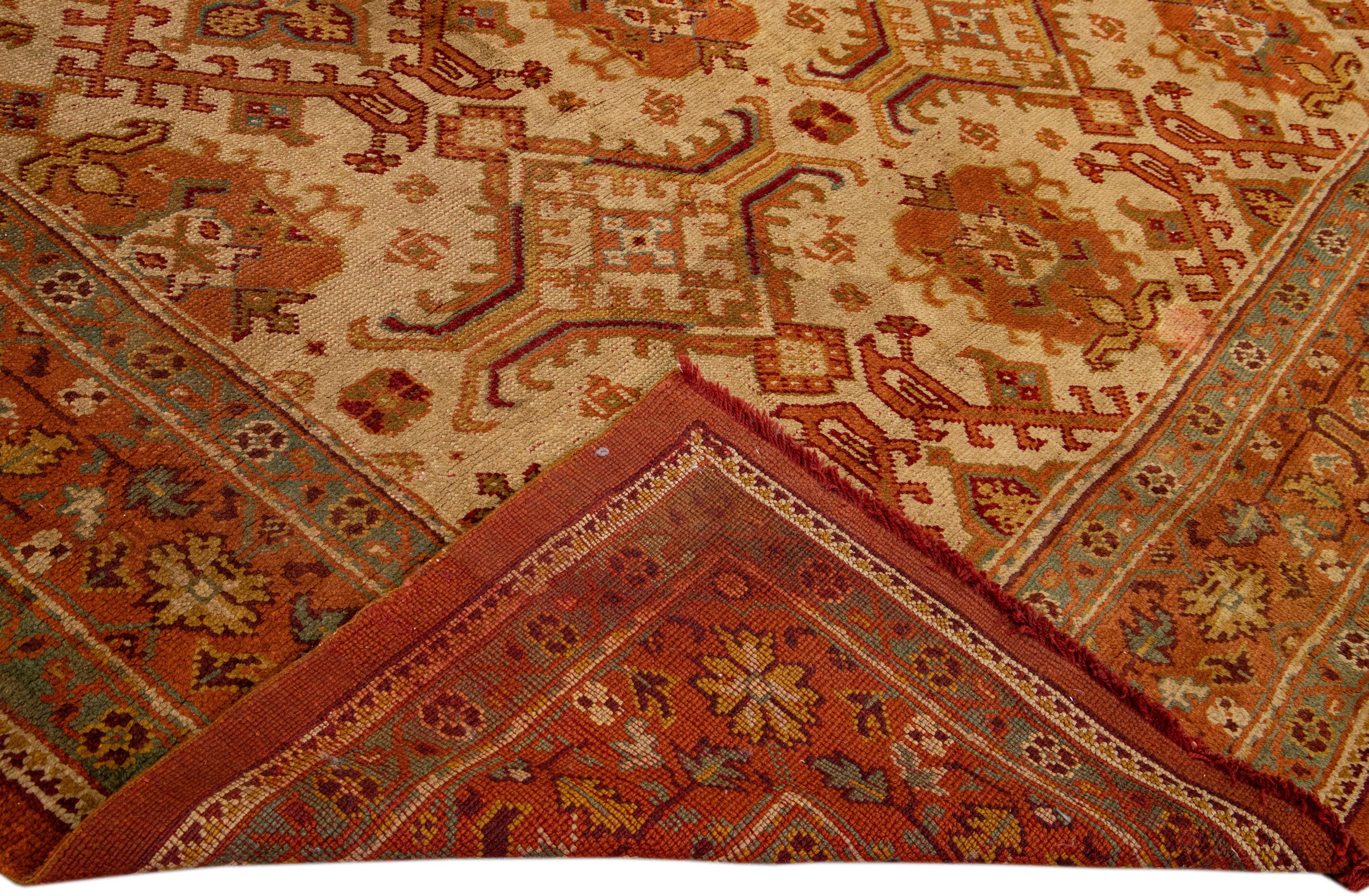 Beautiful Vintage Turkish hand-knotted wool rug with a Tan field. This rug has a designed orange-rust frame with accents of goldenrod and brown in a gorgeous all-over geometric floral design.

This rug measures: 13' x 14'.