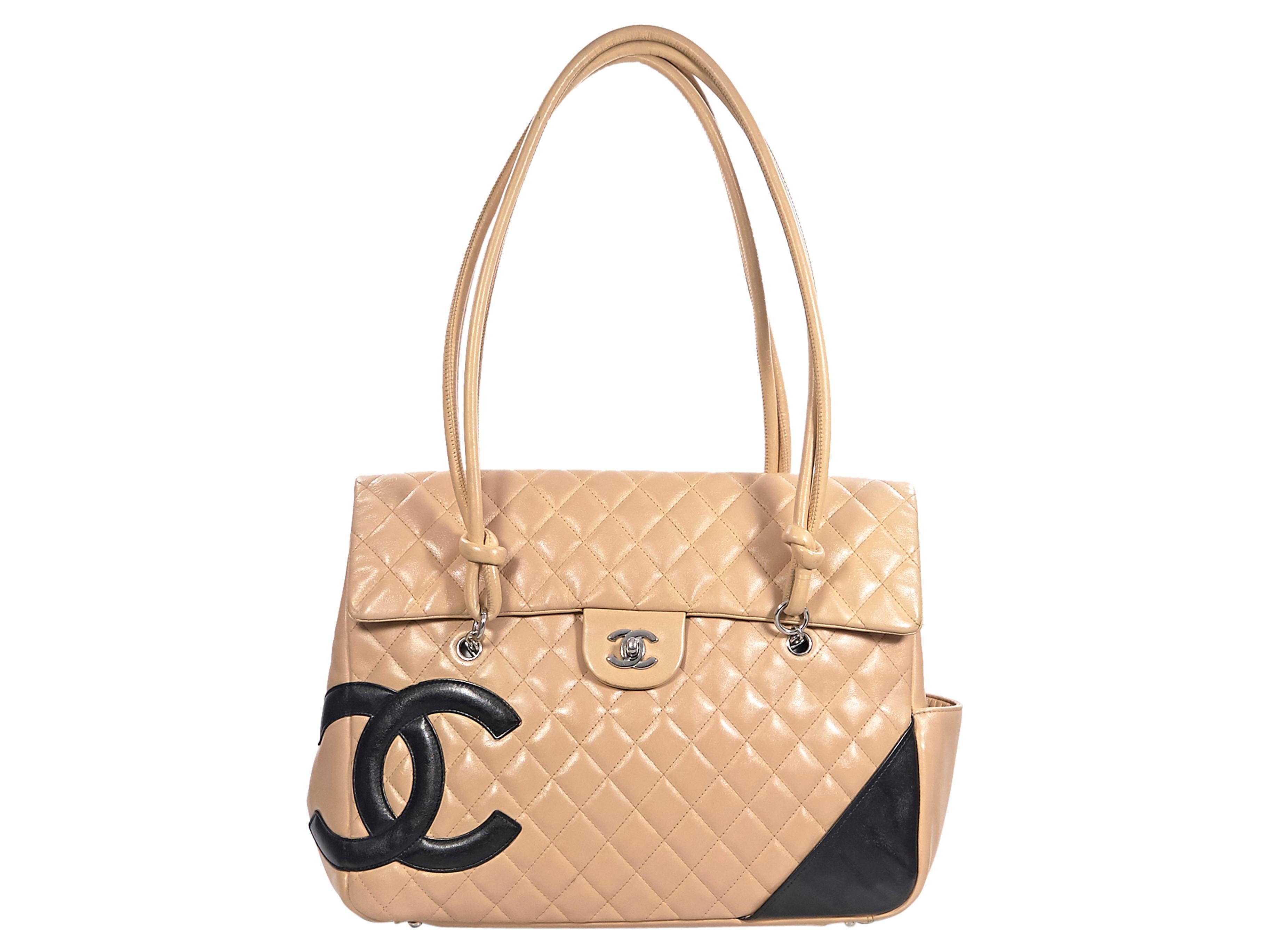Product details:  Tan and black Ligne Cambon quilted lambskin leather flap tote bag by Chanel.  Dual shoulder straps.  Front flap with twist-lock closure.  Lined interior with inner zip pocket.  Exterior side and back slide pockets.  Protective