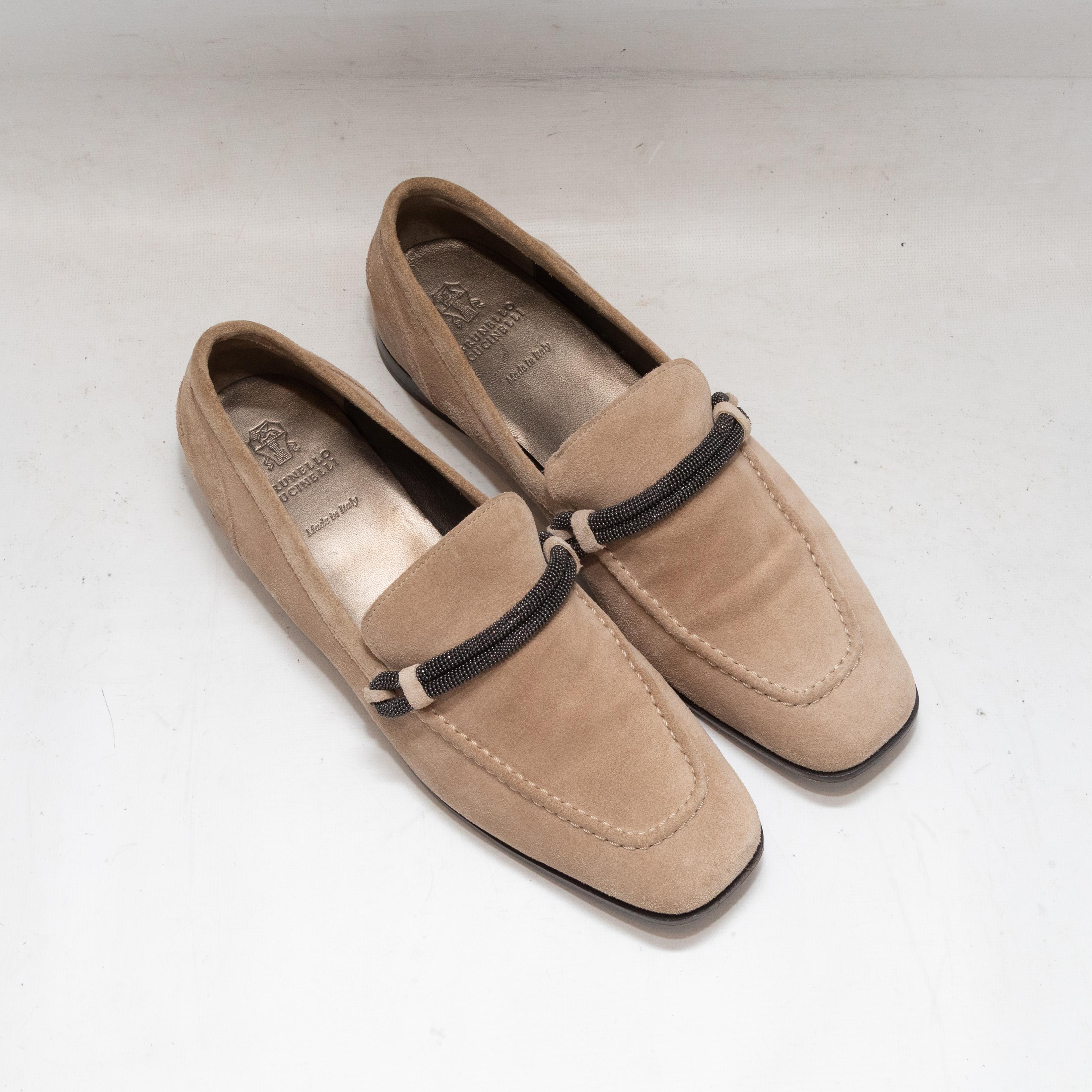 Tan suede loafers by Brunello Cucinelli. Monili trim at tops. Stacked heels. 0.5