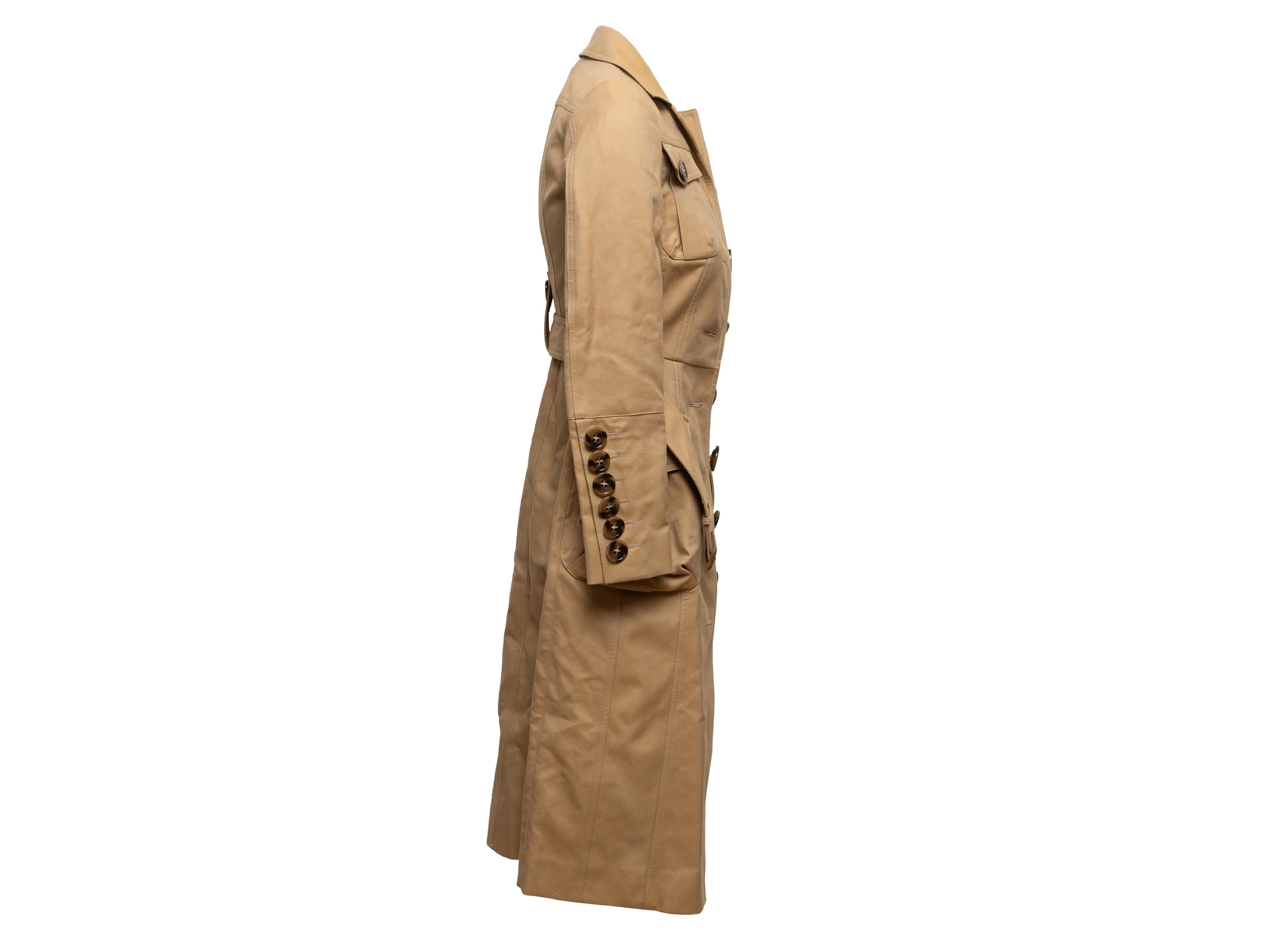 Tan belted trench coat by Burberry Prorsum. Pointed collar. Four pockets. Oversized button closures at front. 30