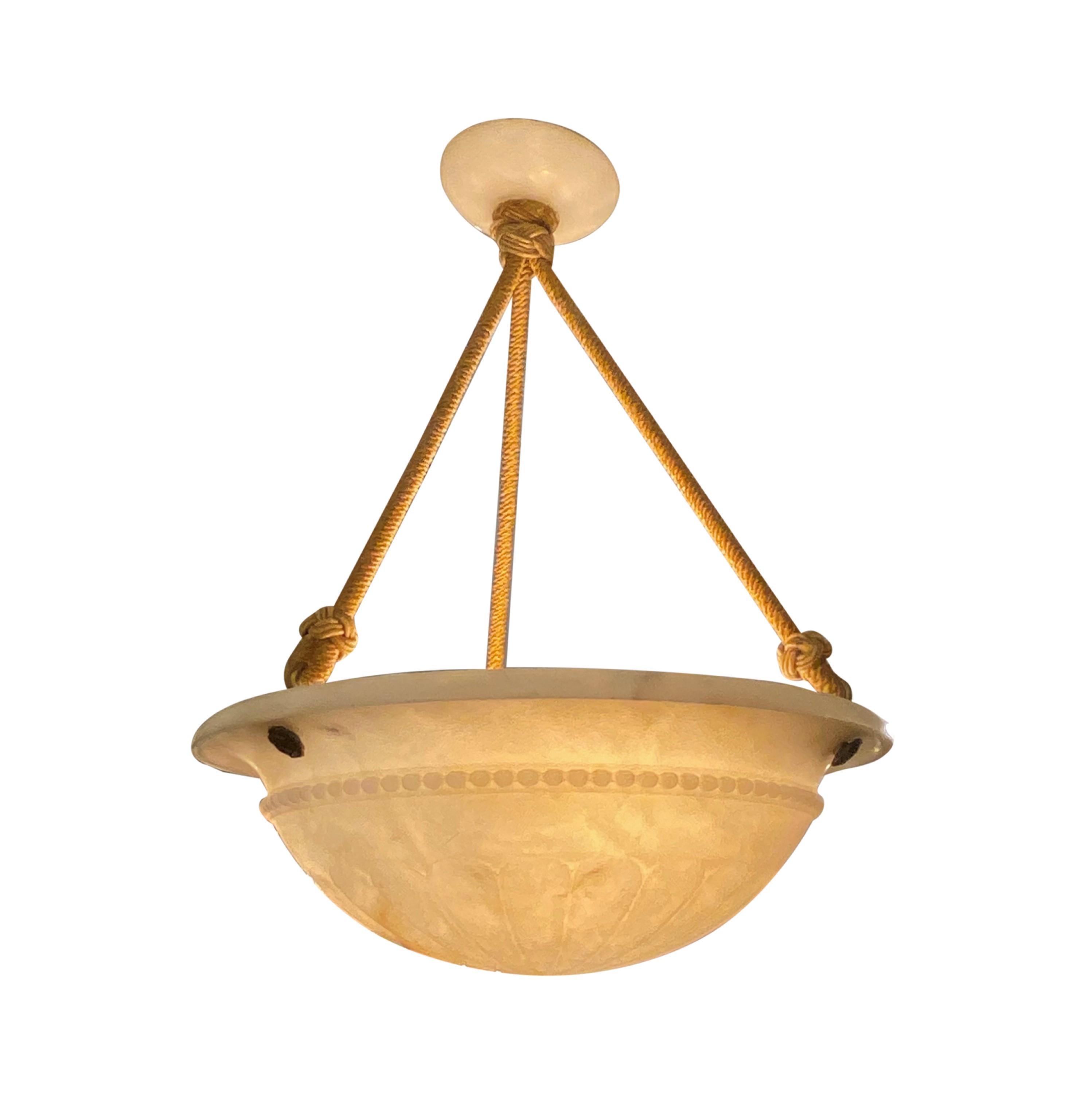 20th century creamy tan colored alabaster dish pendant light featuring carved flowers and beaded details. Also has brass rosette caps and the original yellow rope and canopy. Takes three standard candelabra light bulbs. Cleaned and restored. Please