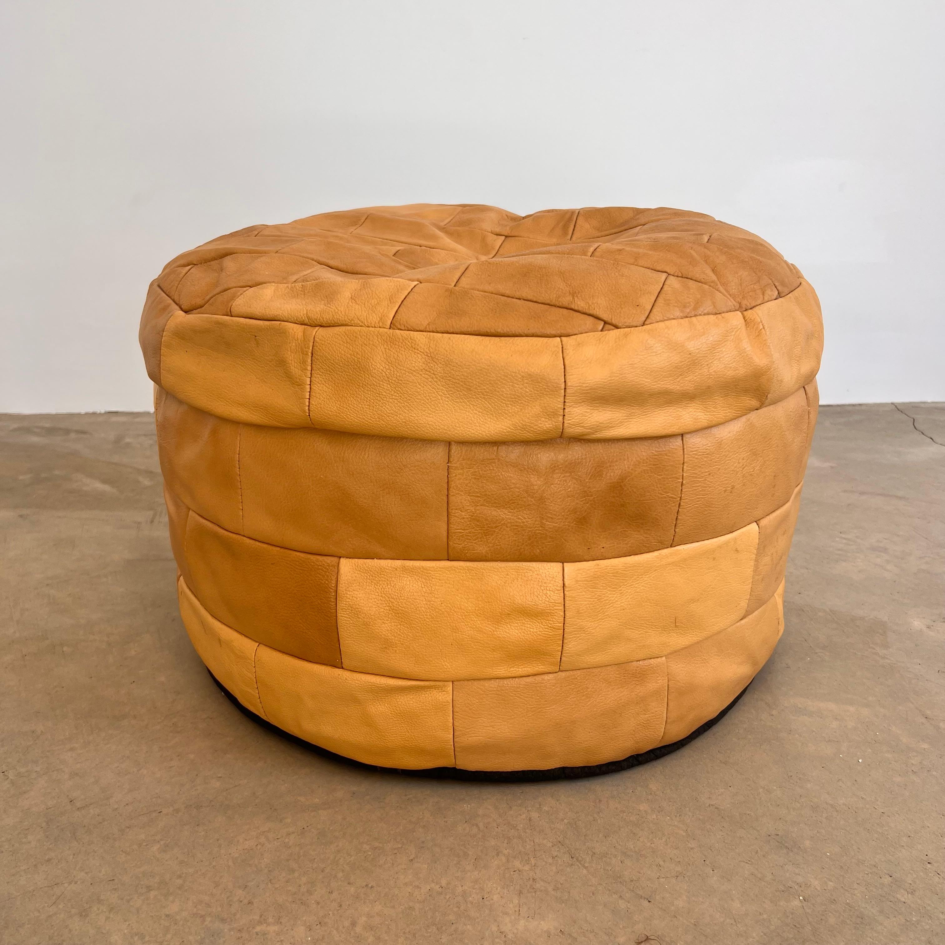 Wonderful and understated tan leather pouf/ottoman by Swiss designer De Sede with square patchwork. Handmade with wonderful faded patina or varying hues of sand and tan. Gorgeous accent piece. Good vintage condition. Wear appropriate with age. Brand