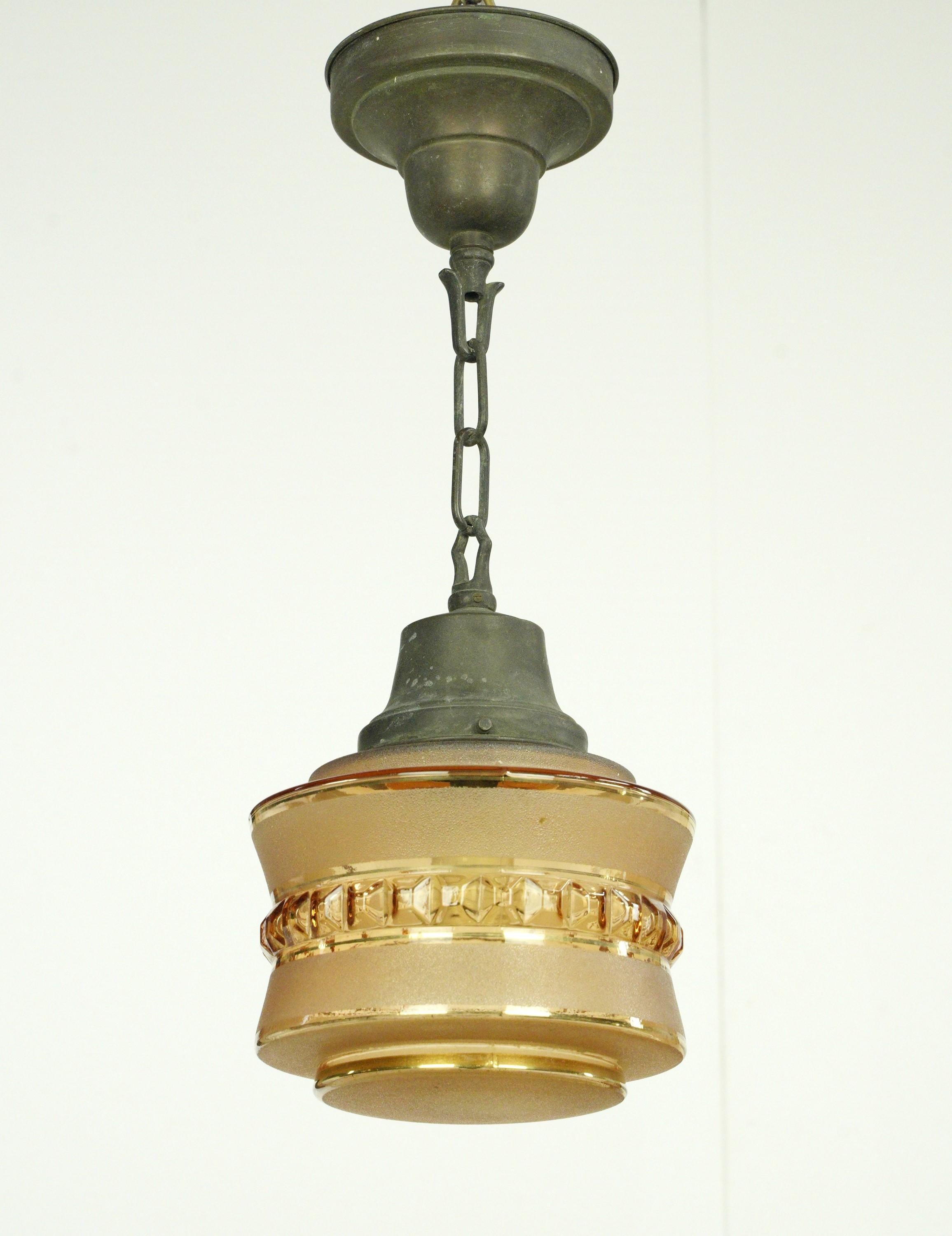 Pendant light with a textured tan globe and bronze chain. This requires one standard medium base bulb. The price includes restoration of cleaning and rewiring. Good condition with appropriate wear from age. One available. Cleaned and restored.