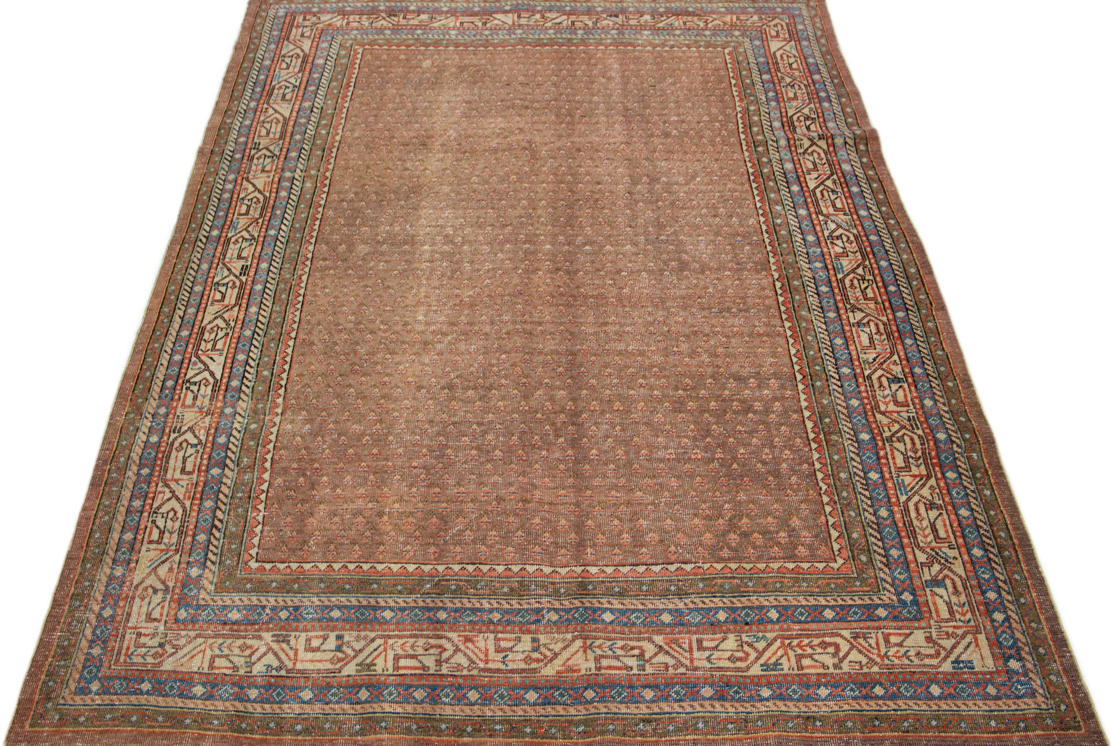 Dieser exquisite antike Hamadan-Teppich ist aus hochwertiger Wolle handgeknüpft und besticht durch ein beigefarbenes Feld, das durch ein fesselndes Allover-Muster ergänzt wird, das mit braunen, pfirsichfarbenen und blauen Akzenten angereichert