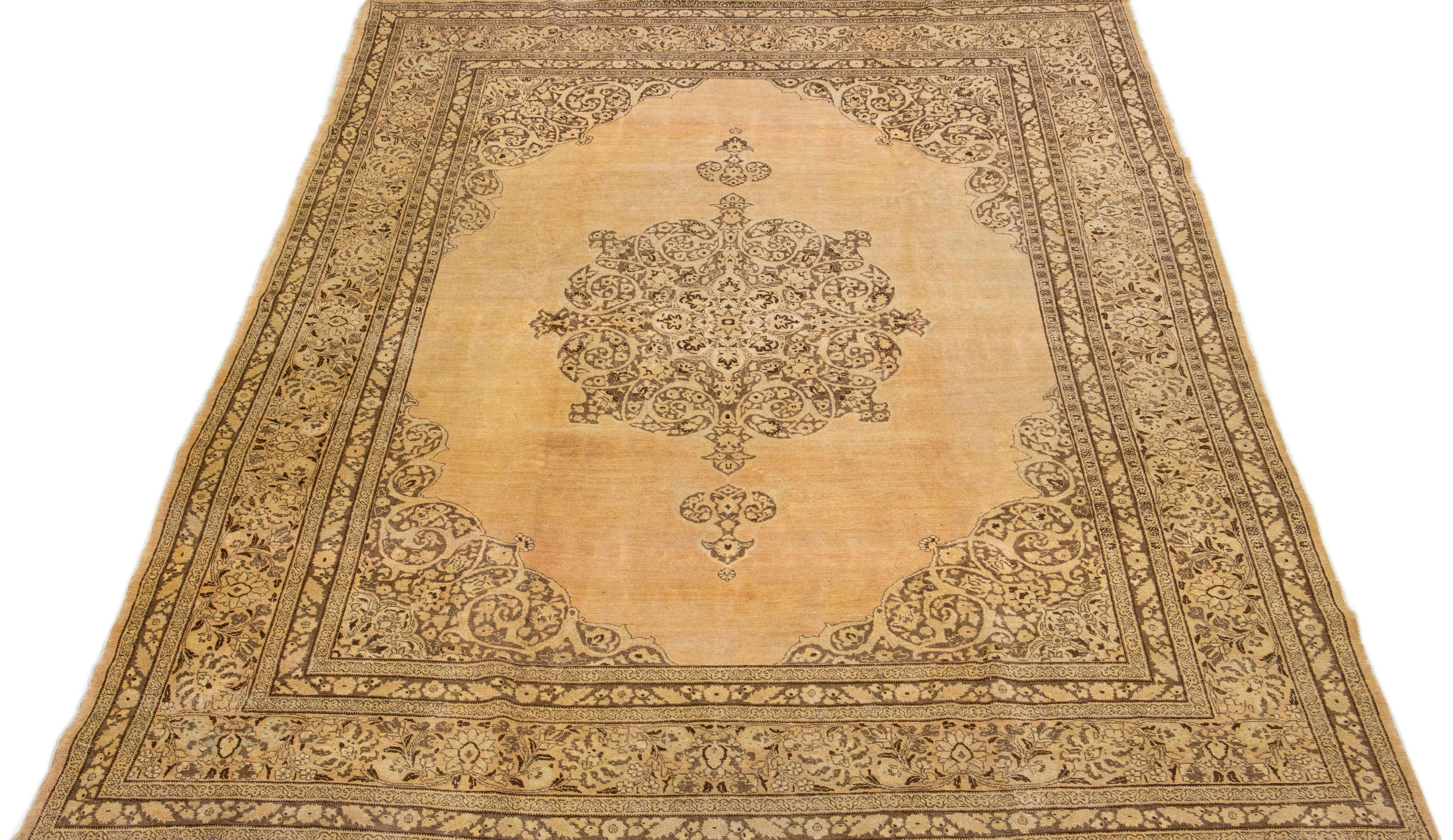 Beautiful antique Persian distressed hand-knotted wool rug with a beige-tan color field. This piece has gray, peach, and brown accents in a gorgeous all-over medallion floral design.

This rug measures: 9'1' x 12'3