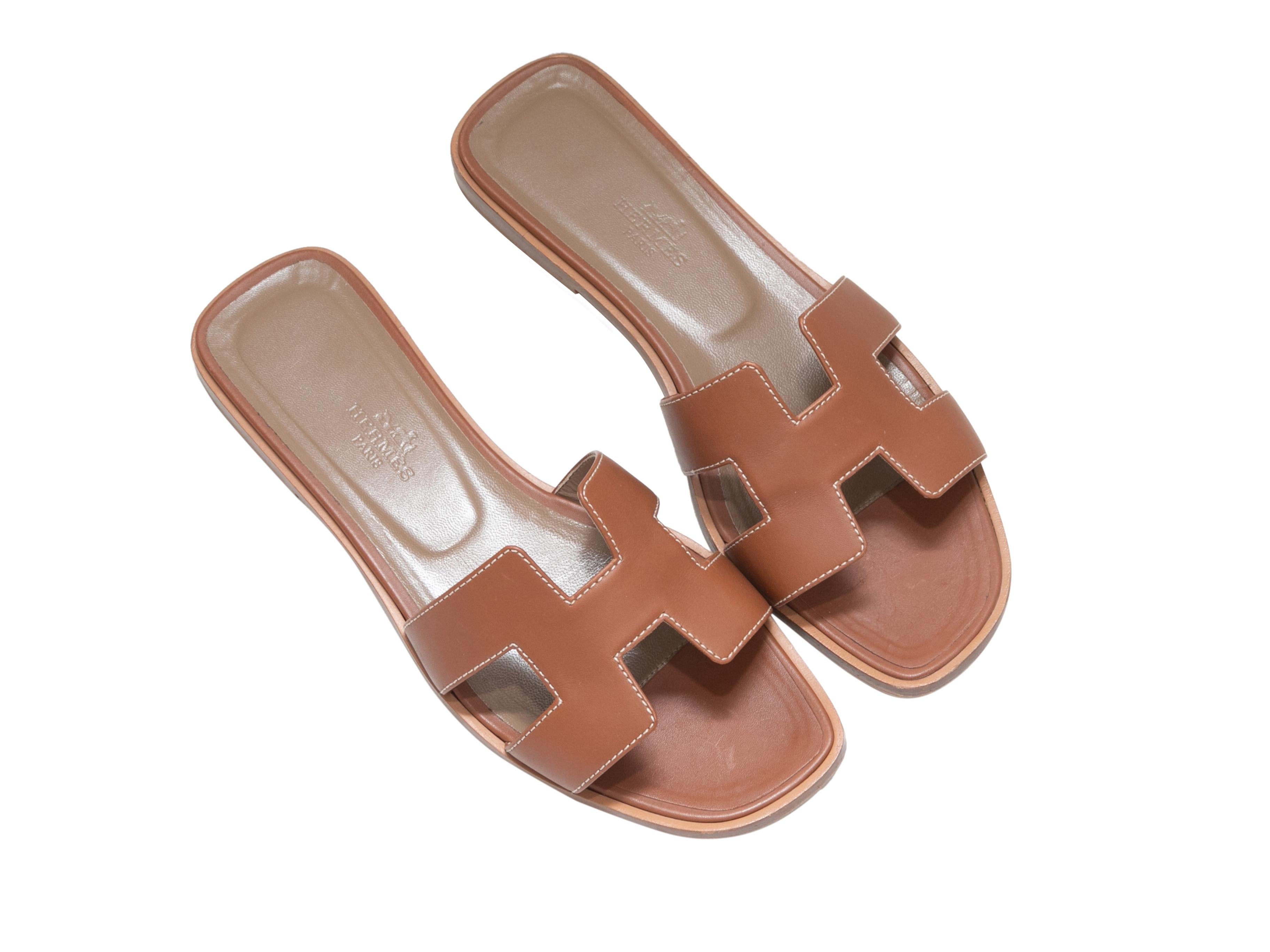 Tan leather flat slide sandals by Hermes. Contrast stitching throughout. Stacked heels. 1