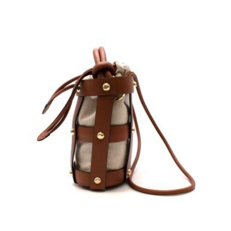 Salvatore Ferragamo tan leather & natural canvas Cage bucket bag
 
 
 
 - Hammered calf leather cage-like exterior with gold-tone metal studs
 
 - Unstructured inner canvas pouch with drawstring opening
 
 - Tube handle with removable crossbody