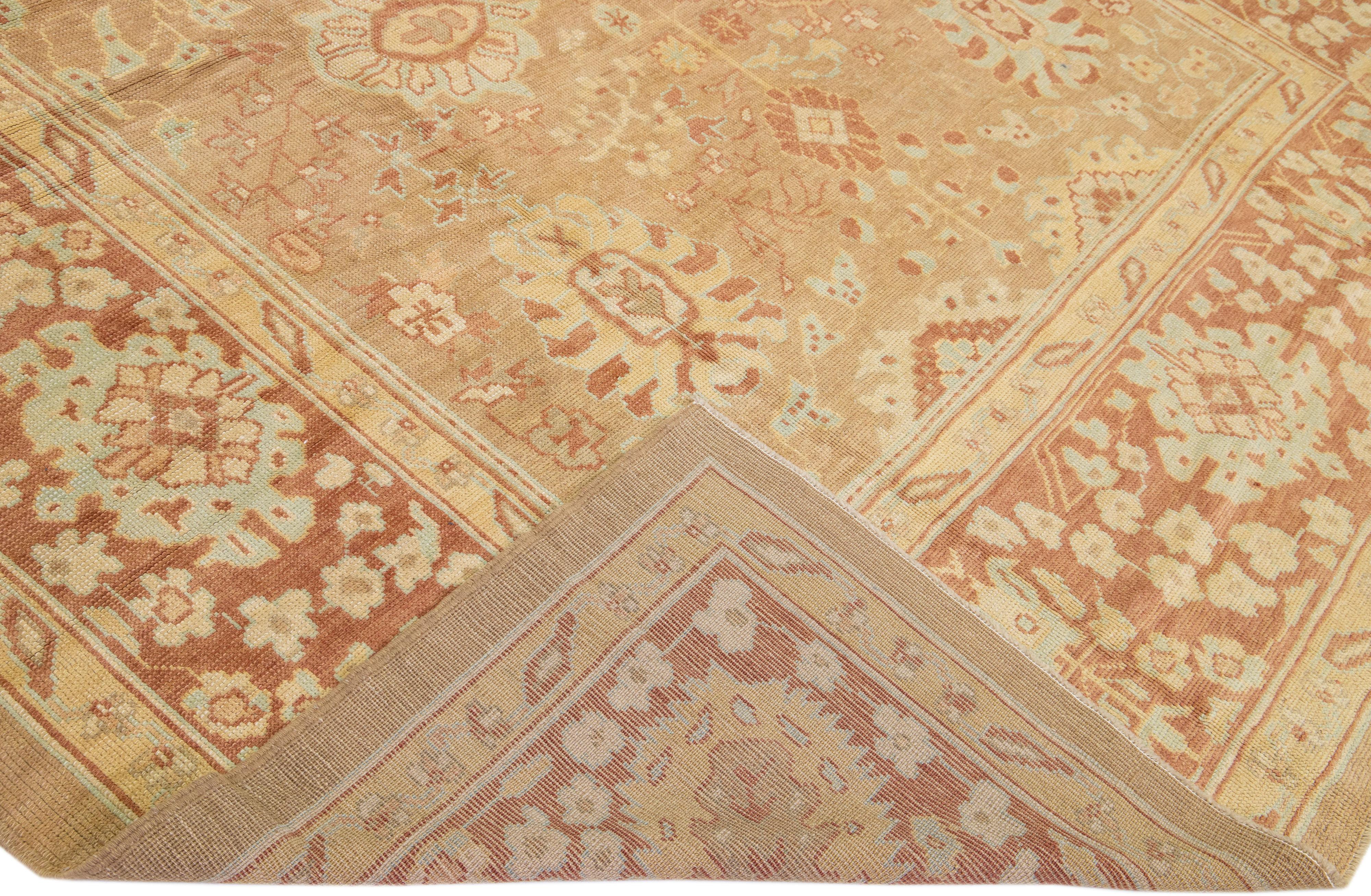 Beautiful modern Oushak hand-knotted wool rug with a tan color field. This Turkish Piece has a rusted-designed frame with blue and peach accent colors in a gorgeous all-over floral design.

This rug measures: 10'8