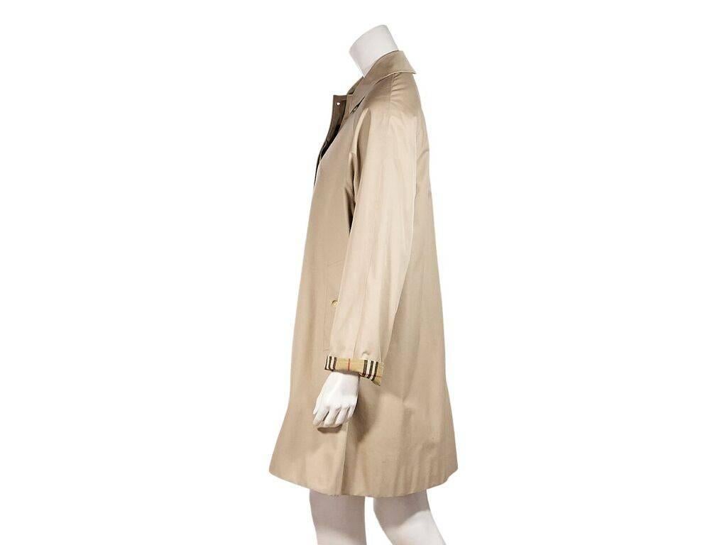 Product details:  Vintage tan oversized trench coat by Burberry.  Spread collar.  Long dolman sleeves.  Concealed button-front closure.  Button waist slide pockets.  52
