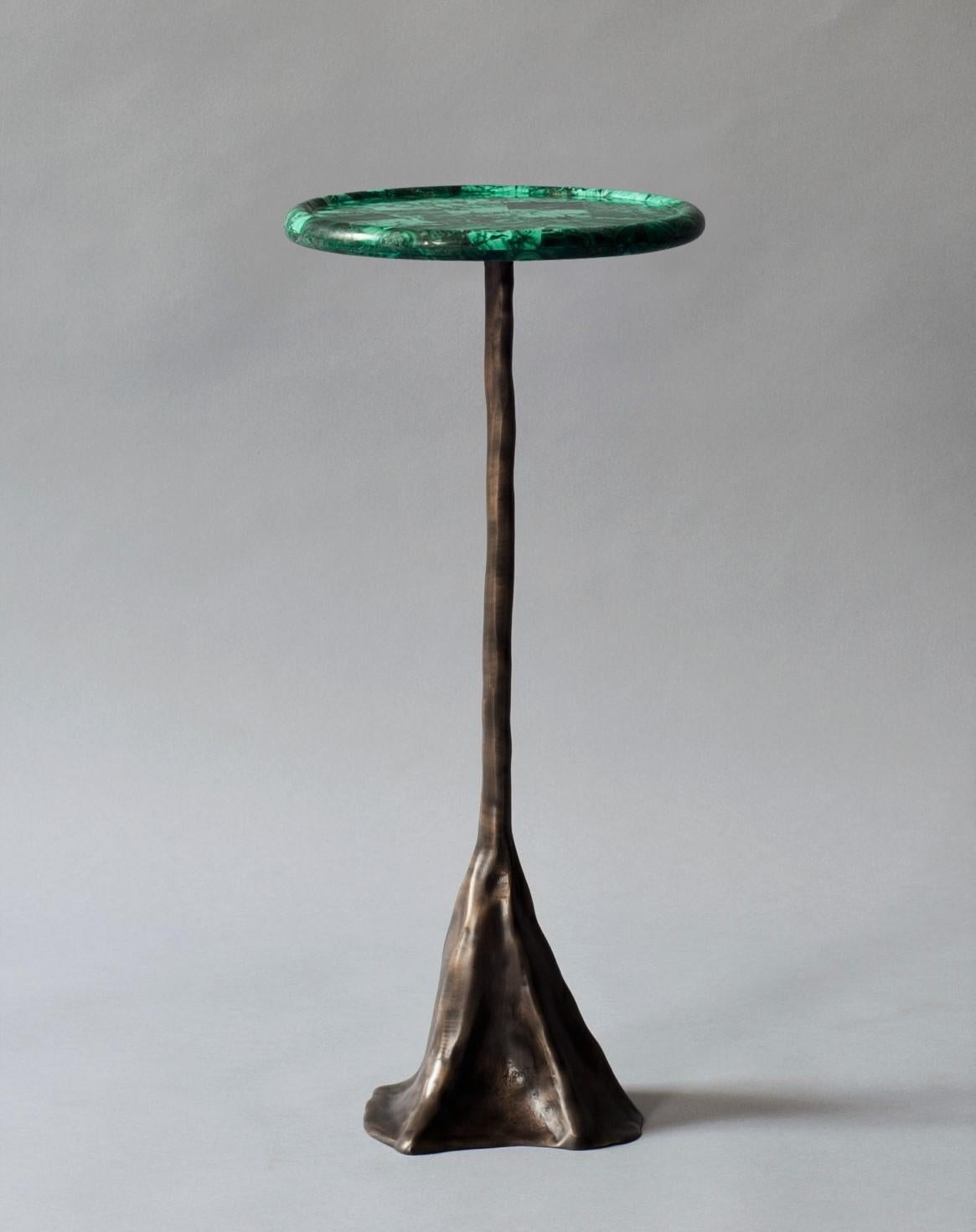 The Tana side or drinks table by DeMuro Das has a circular tray top in Malachite supported by a sculptural, hand-cast solid antique bronze base.