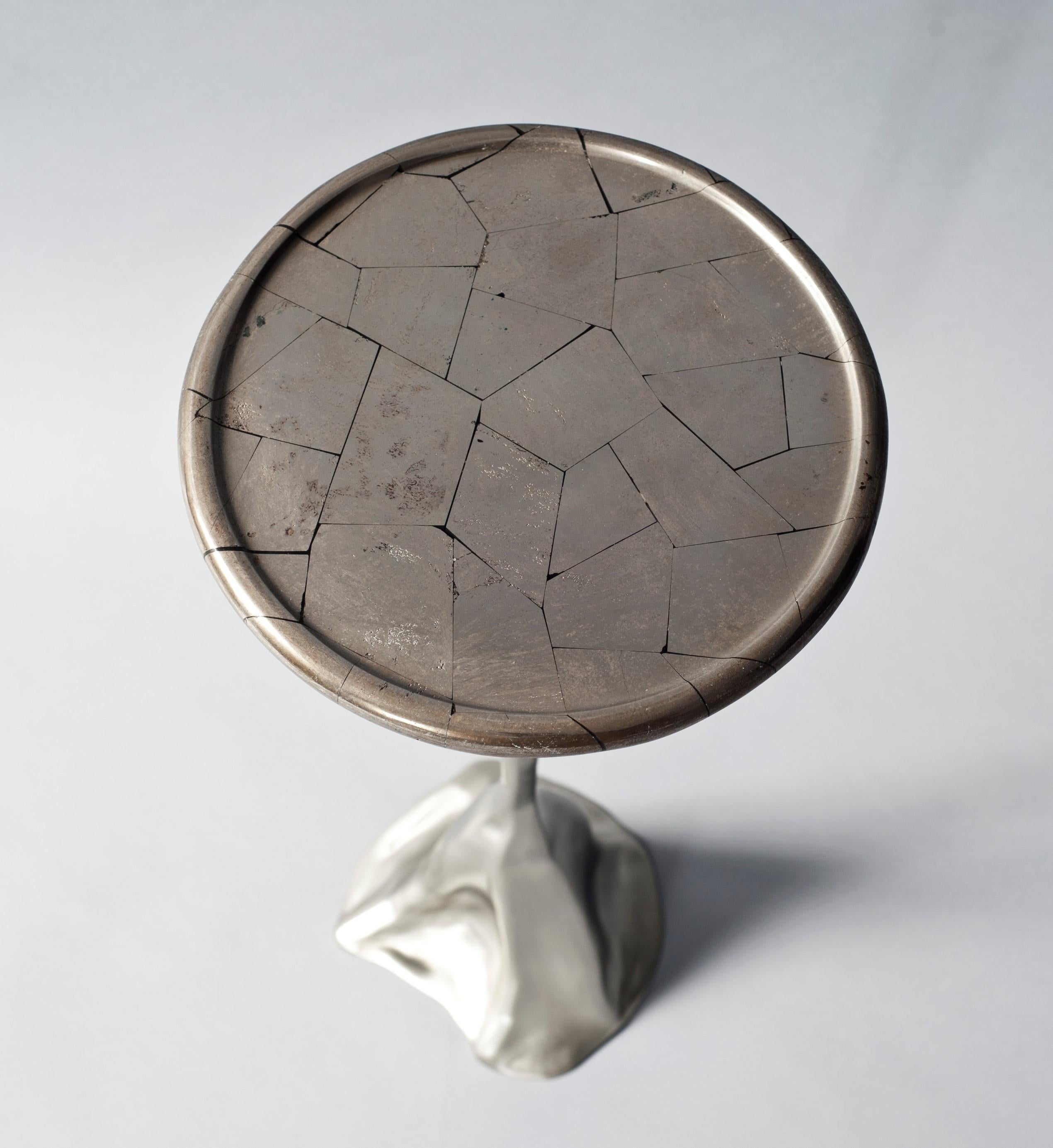The Tana side or drinks table by DeMuro Das has a circular tray top in silver pyrite supported by a sculptural, hand-cast solid nickel silver base.