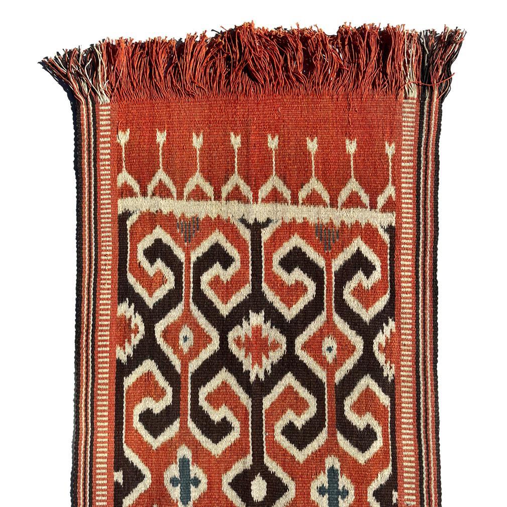 Tana Toraja Sekomandi Ikat Selendang (étoffe d'épaule, foulard, suspension murale), Sulawesi, Indonésie. Ce textile ikat de chaîne est un panneau unique tissé. Les fils de coton sont teints à la main en utilisant  rouge végétal, bleu et noir,