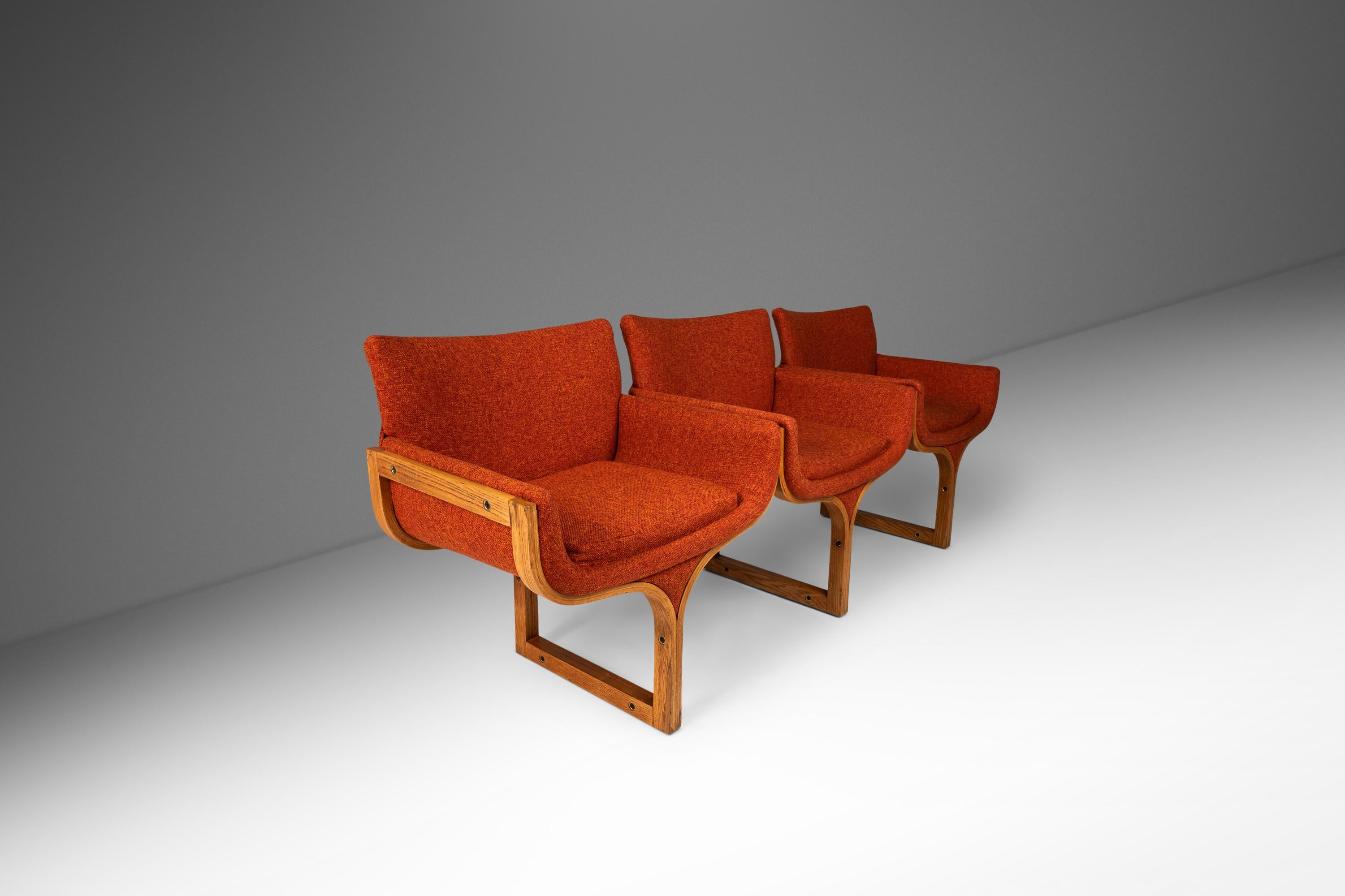 The Three Seat Architectural Bench by Arthur Umanoff for Madison Furniture is a stunning example of mid century modern design. Constructed from laminated oak plywood and newly upholstered in a muted tangerine knit fabric, this piece has been fully