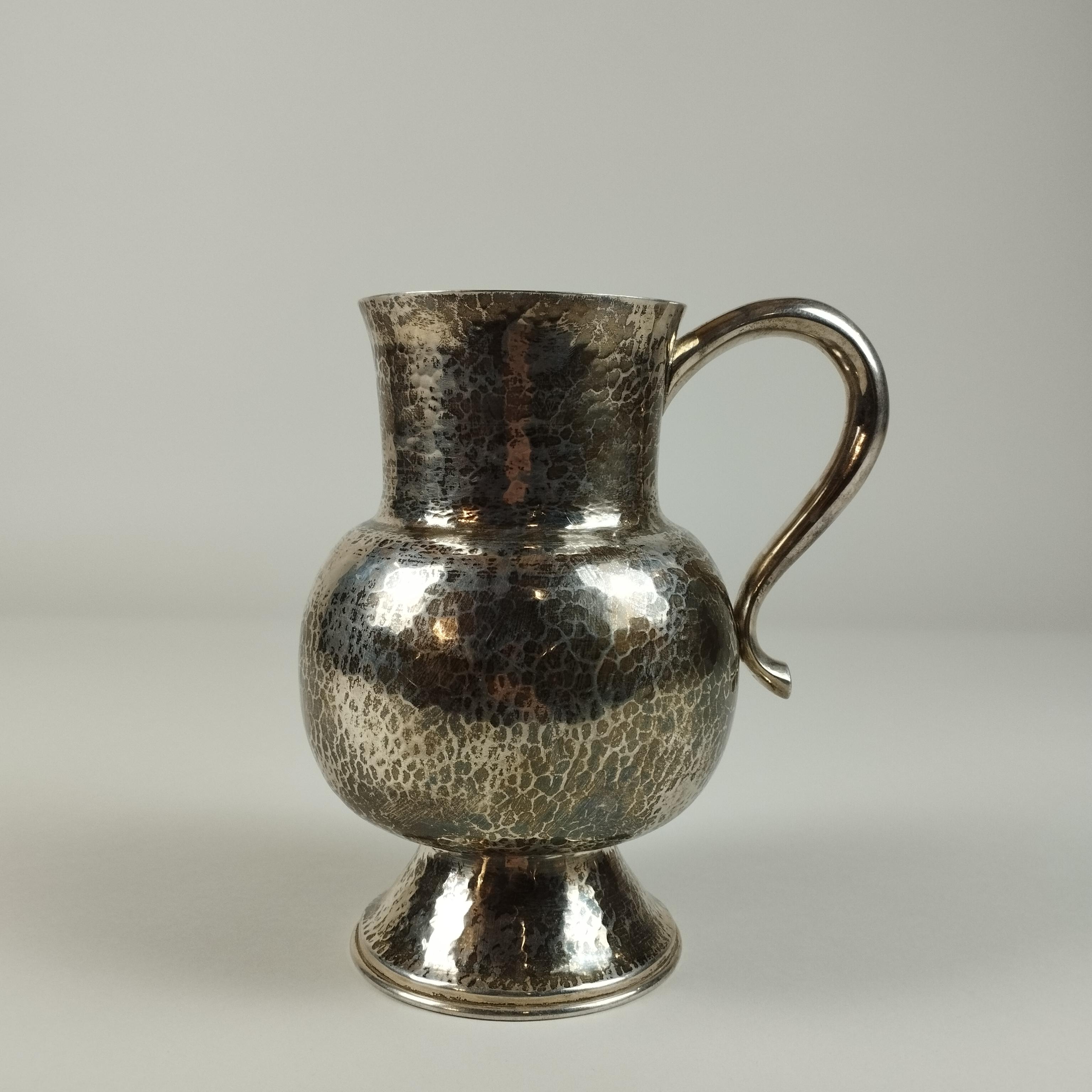 A Mexican mid-century modern Sterling silver pitcher by Tane Orfebres. The pitcher's body is hammered.

The pitcher's weight is 1039 grams. (33.4046 Troy ounces).

Tane Orfebres was founded in 1942 in Mexico City by Sergio and Natalia Leites, a