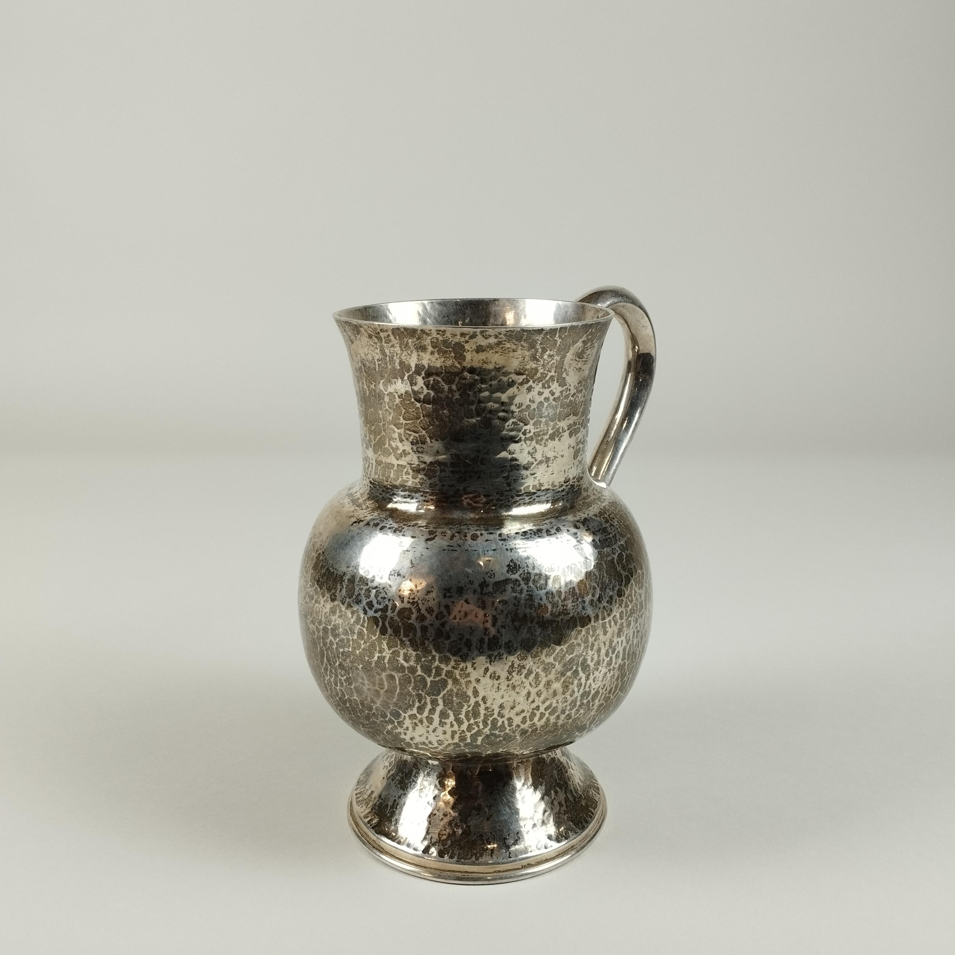 A Mexican mid-century modern Sterling silver pitcher by Tane Orfebres. The pitcher's body is hammered.

The pitcher's weight is 1039 grams. (33.4046 Troy ounces).

Tane Orfebres was founded in 1942 in Mexico City by Sergio and Natalia Leites, a