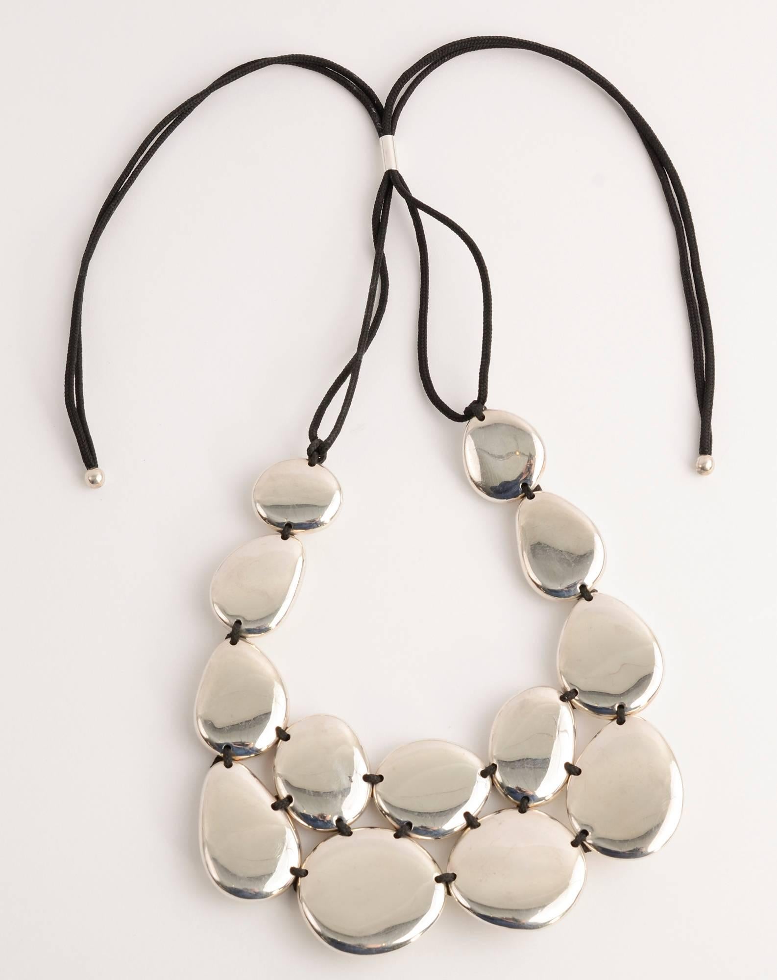 Stylish and versatile silver necklace by Tane, known as Mexico's equivalent of Tiffany.
The necklace is made of 13 silver medallions of varying shapes and sizes. They are strung on a woven cloth cord. The knotted intersections with which they are