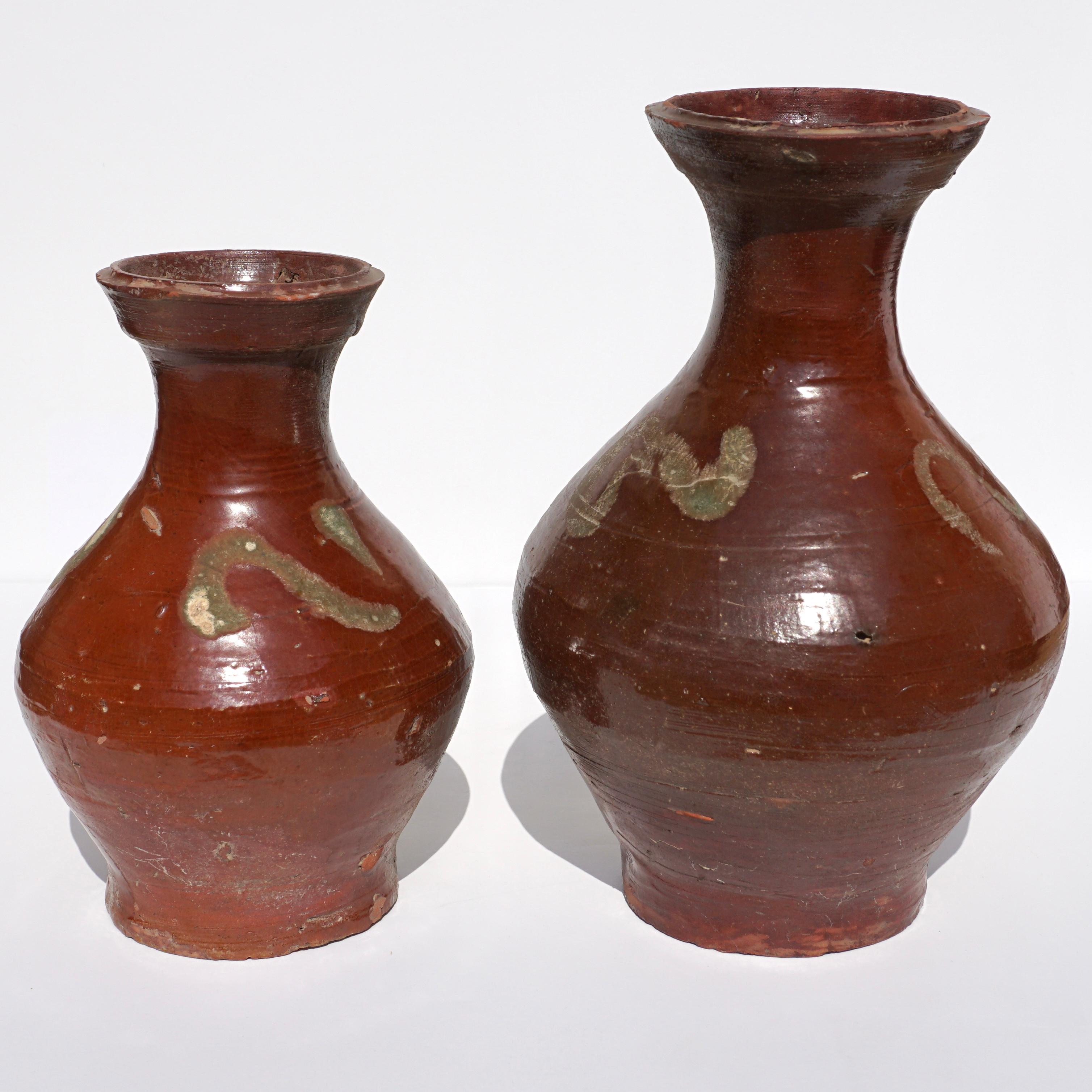 C. AD 618-907. Tang Dynasty. 

Two beautiful terracotta pottery jars covered with a ox blood to chestnut-coloured glaze. The bulbous bodies taper into a slender neck with flared rim. The shoulders are decorated with wavy pattern swishes.

It was not