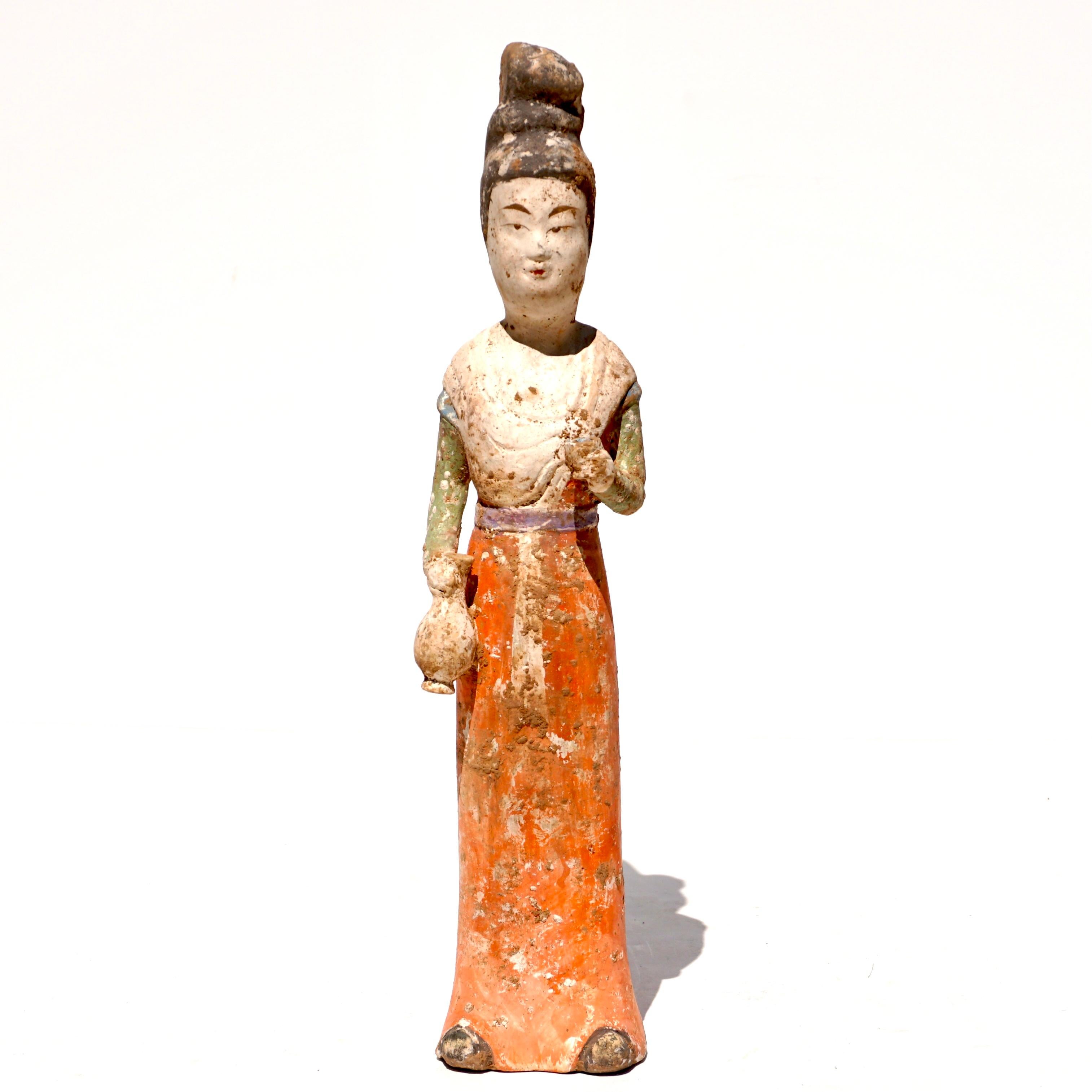 Circa 618-907 ADA mold-formed pottery tomb attendant figure in the form of a woman who is wearing a lengthy robe with a red-painted skirt, upper clothing in green, her left arm by her side holding a vessel and her right hand outstretched, she is