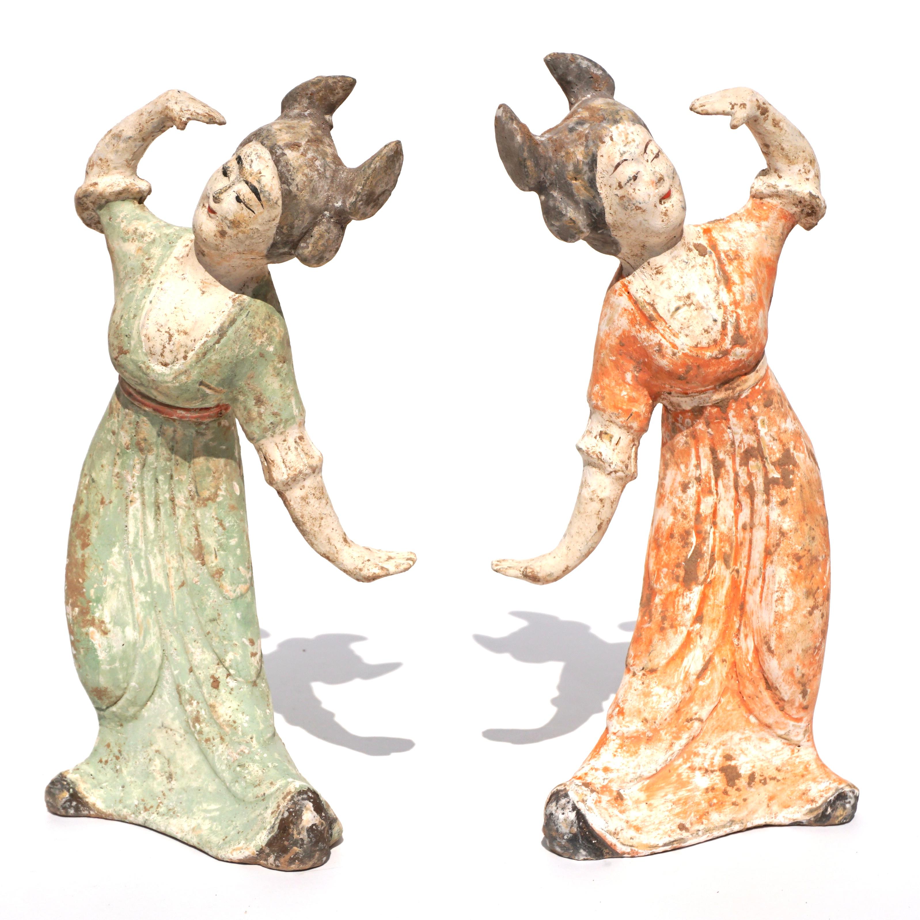 C. AD 618 and 907. Tang Dynasty. 

A delicate Tang Dynasty pair of female dancer figures. Both wearing long flowing gowns with the hands uncovered. One dress is a deep orange, whilst the waist sash which separates the skirt from the bodice is of