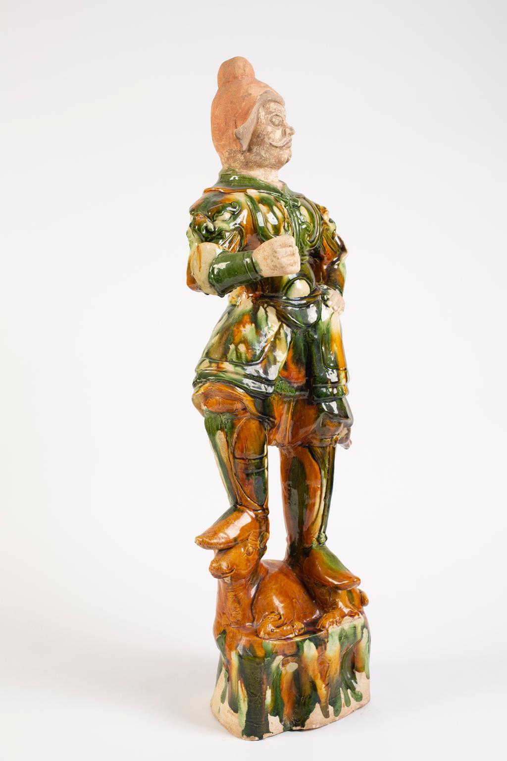 Chines Tang Dynasty sancai glazed pottery figure of a Guardian is a protector of the deceased. This warrior dressed in armor with a fierce face and imposing position would accompany the dead into the next life. Only the wealthy could afford such