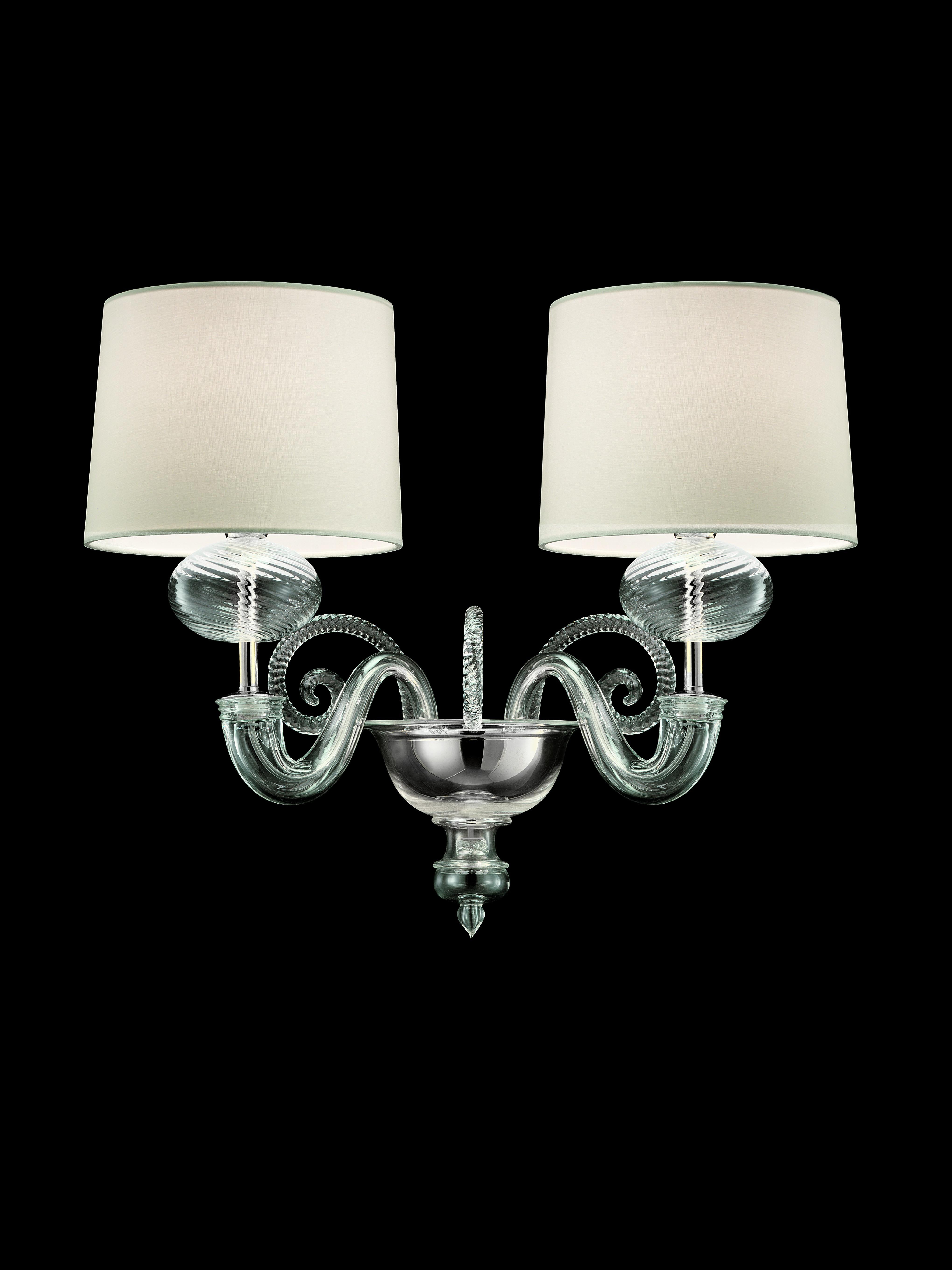 Shown here is the Tangeri 5604 02 wall sconce in crystal glass and a polished chrome finish, with a White Shade. The light collection was inspired by the palaces and emotions of sunset in Morocco, Tangeri is a wall sconce with two arms in crystal