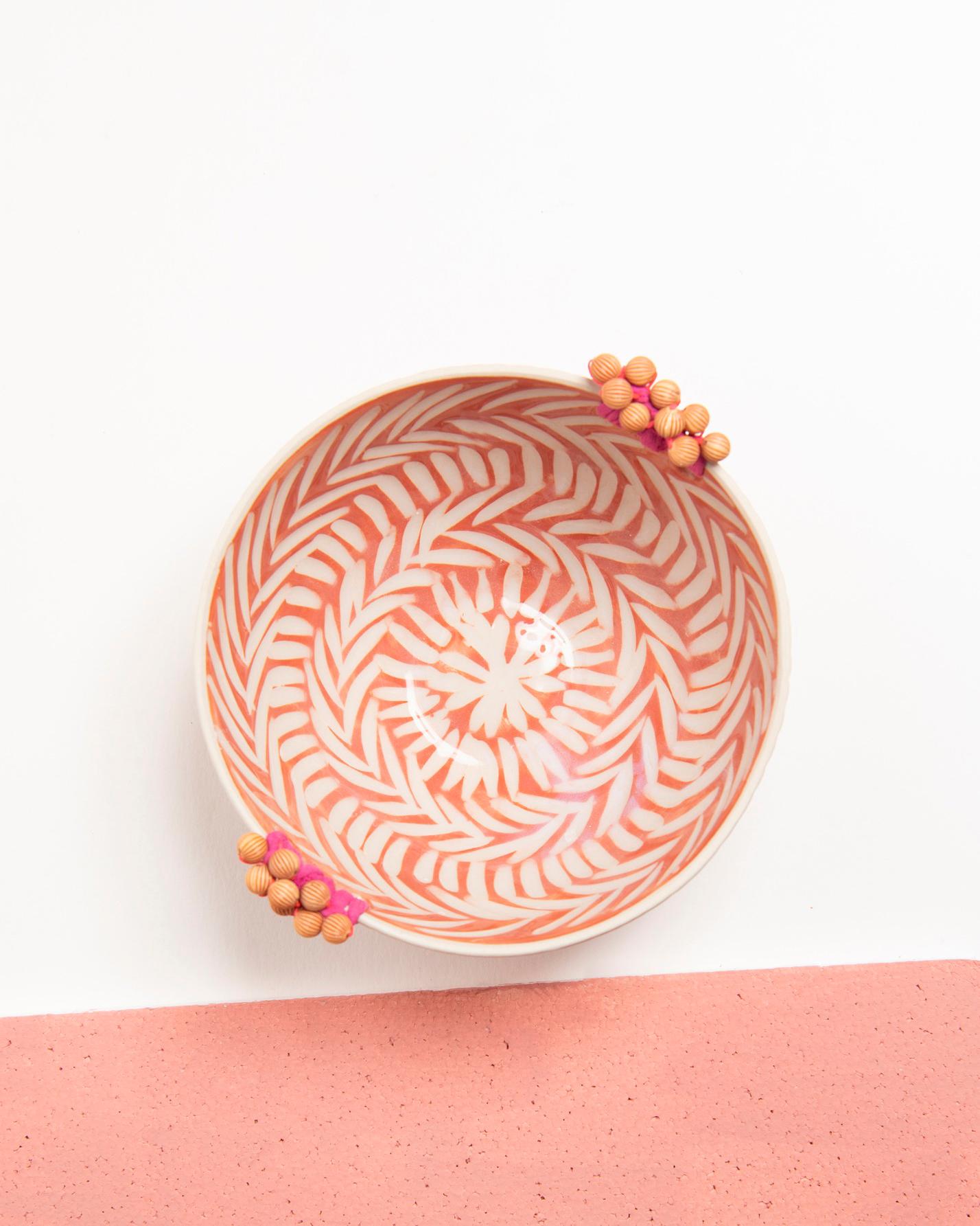 A colorful bowl for your mantle
This handcrafted ceramic bowl is rustically European with whimsical details like colorful beads and cotton thread. Its rustic pinkish orange and white tones bring a touch of charm to home decor, whether placed atop a