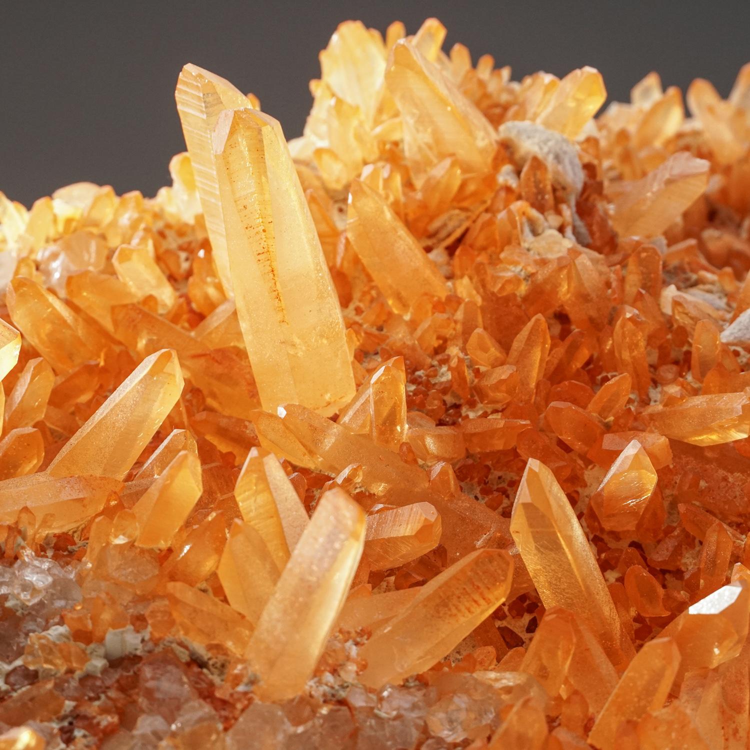 A large cluster of rare, orange tangerine quartz crystals, from the northern territory of Minas Gerais, Brazil. These rare quartz clusters are only found in this region of the world. A hematite oxidate within the quartz has created the orange color.