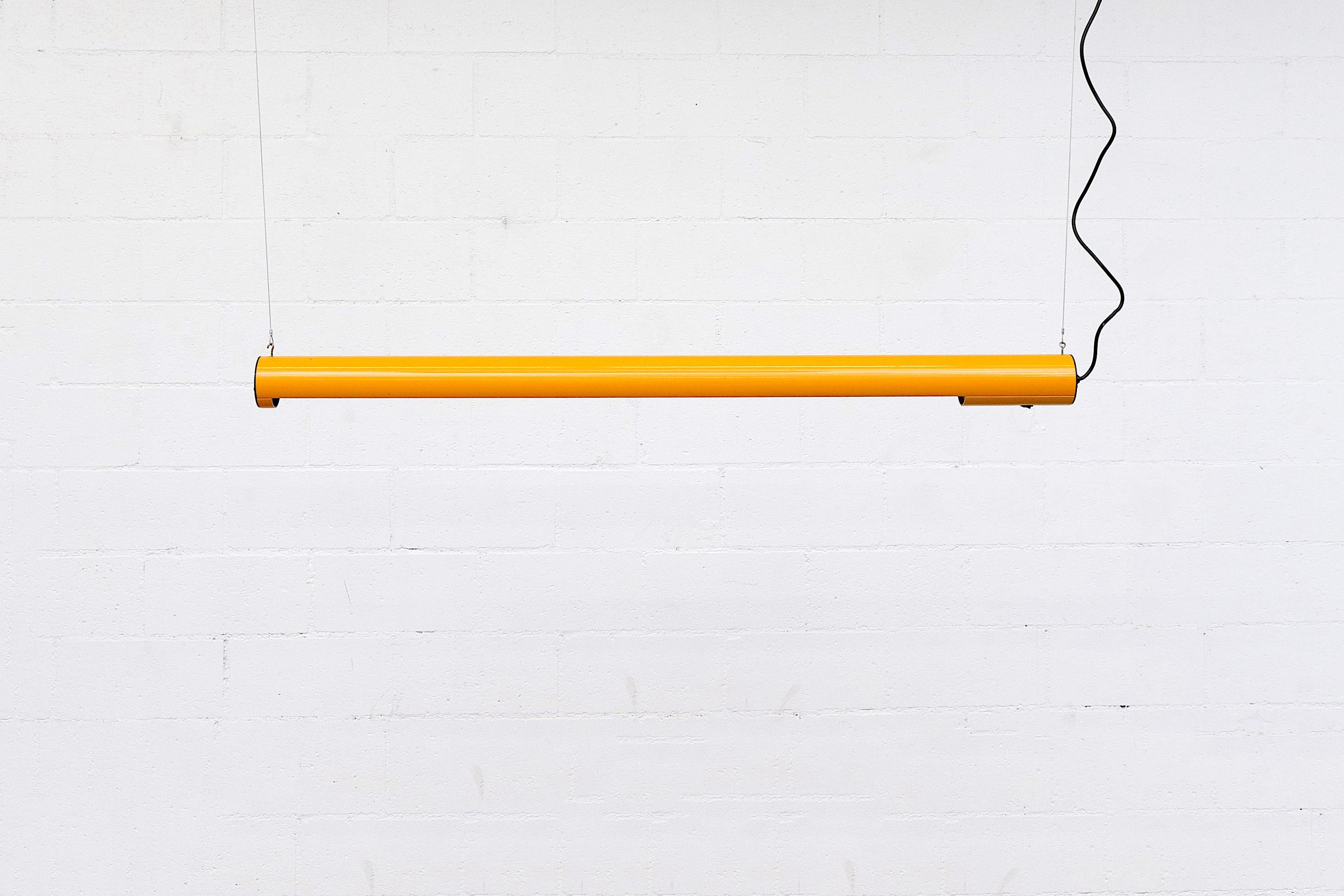 Enameled Tangerine tubular florescent light, suspended by 2 cables or chain. Actual tube measures 56.625