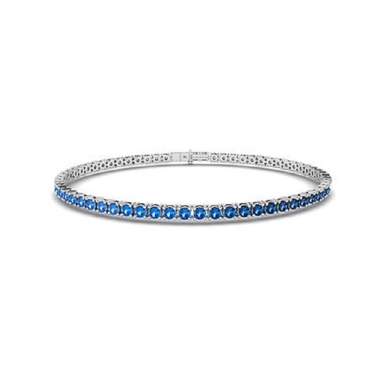 The Ombre Blue Sapphire Tennis Bracelet in 18K gold showcases a mesmerizing gradient of blue sapphires, seamlessly transitioning from deep navy to light azure. Set in a sleek, continuous line, this bracelet brings vibrant color and elegance to any