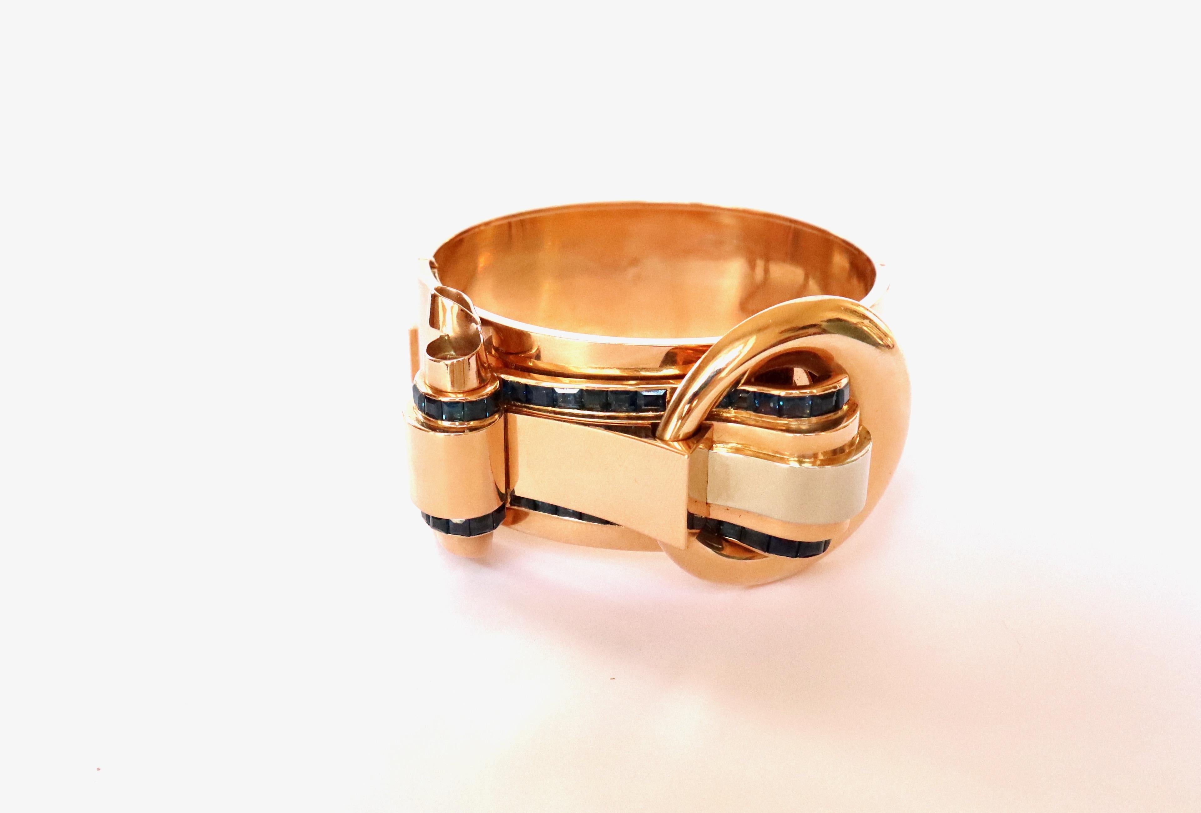 TANK Bracelet around 1940 Rigid opening with Buckle Pattern in 18 Carats yellow Gold rose gold and white gold and Calibrated Sapphires serrated two Rails on the motif, with a Safety Chain. 
Size: Oval, inside of the Bracelet: Width: 6 cm Height: 5