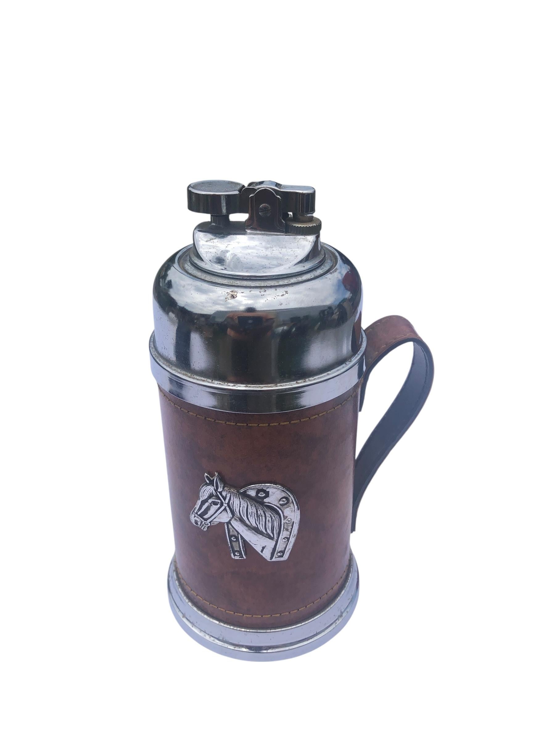 Tankard Cigarrillo y Encendedor de Piel con Decoración de Cabeza de Caballo. De cuero marrón con una decoración de cabeza de caballo aplicada, el encendedor incorpora un ingenioso compartimento oculto que se levanta para revelar un lugar donde