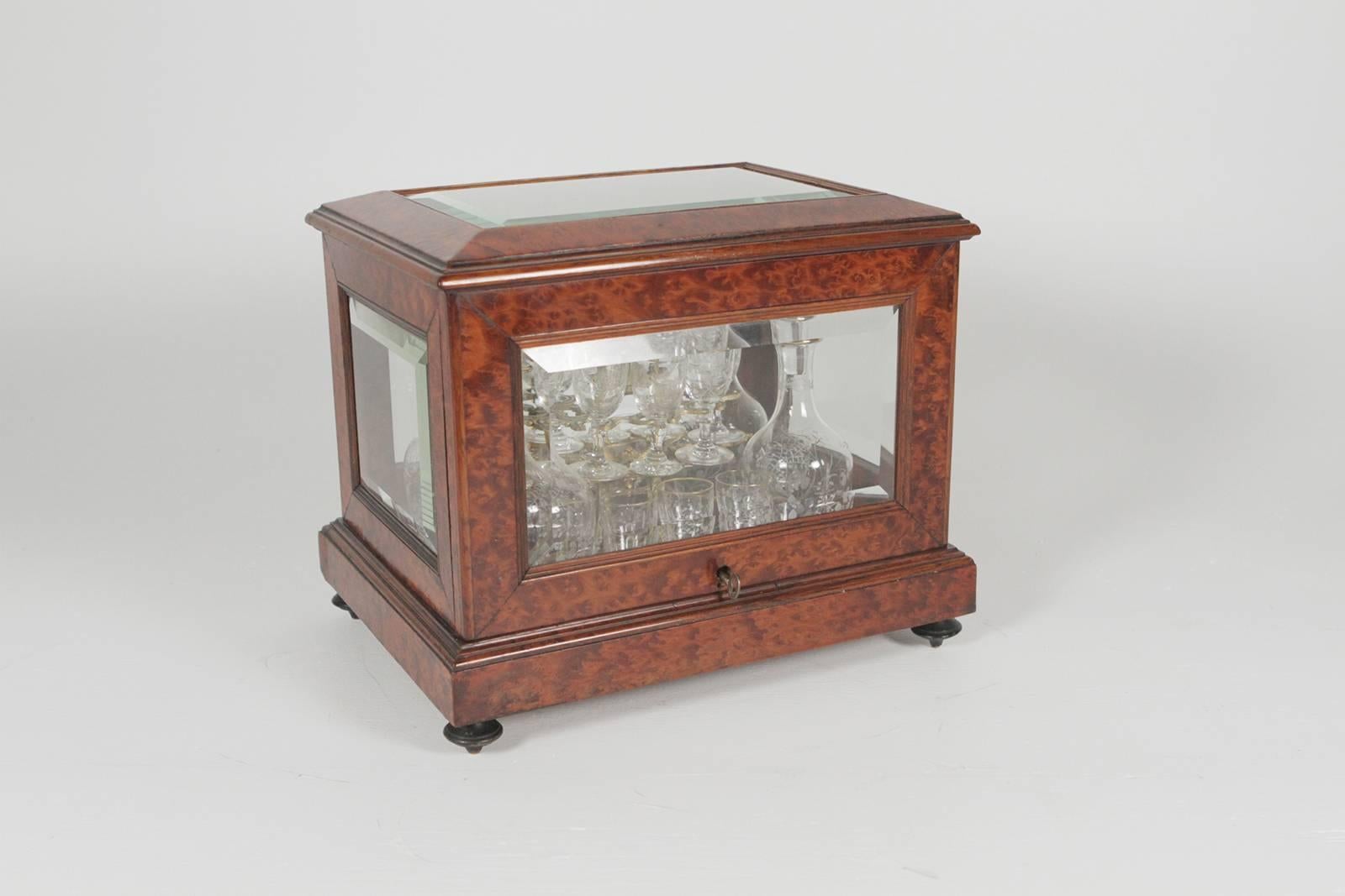 A glass and burled walnut Tantalus with four decanters and 14 matching cordials. The beveled glass panes with warm burled walnut frames and bottom. The crystal is edged in gold with delicate engraved design. The crystal is attributed to Baccarat.