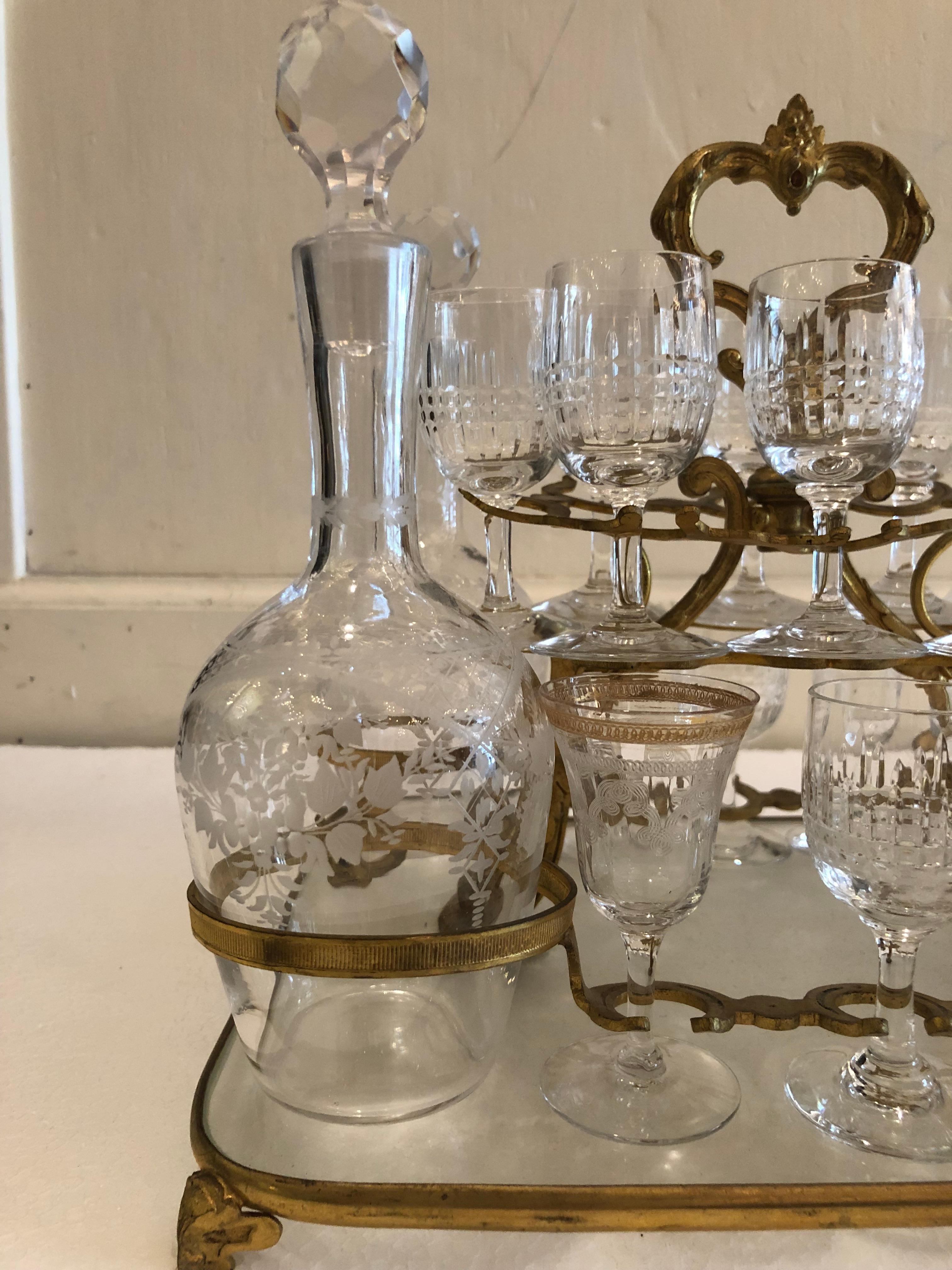 Tantalus set with Baccarat glasses- A gilt bronze and glass tantalus stand with 4 etched glass decanters, 14 cordial glasses (4 are etched with gold rims, 10 are signed Baccarat). Together with a three piece cut glass decanter set housed in a