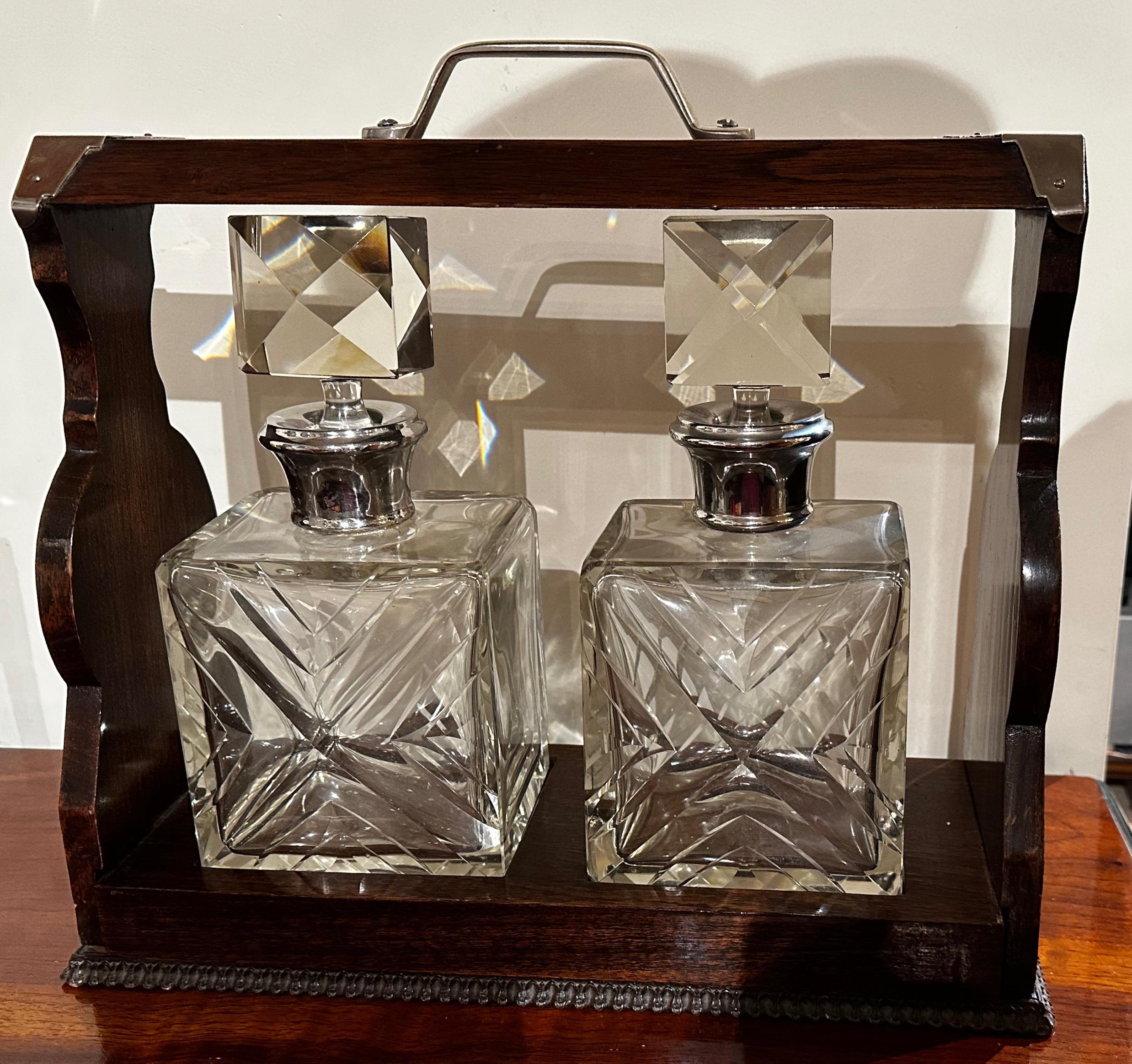 Tantalus two Decanter Art Deco set with wood holder is a beautiful and functional piece of barware that adds to the culture and distinction from the art of the cocktail. This set includes two decanters and a wooden holder, all designed with the