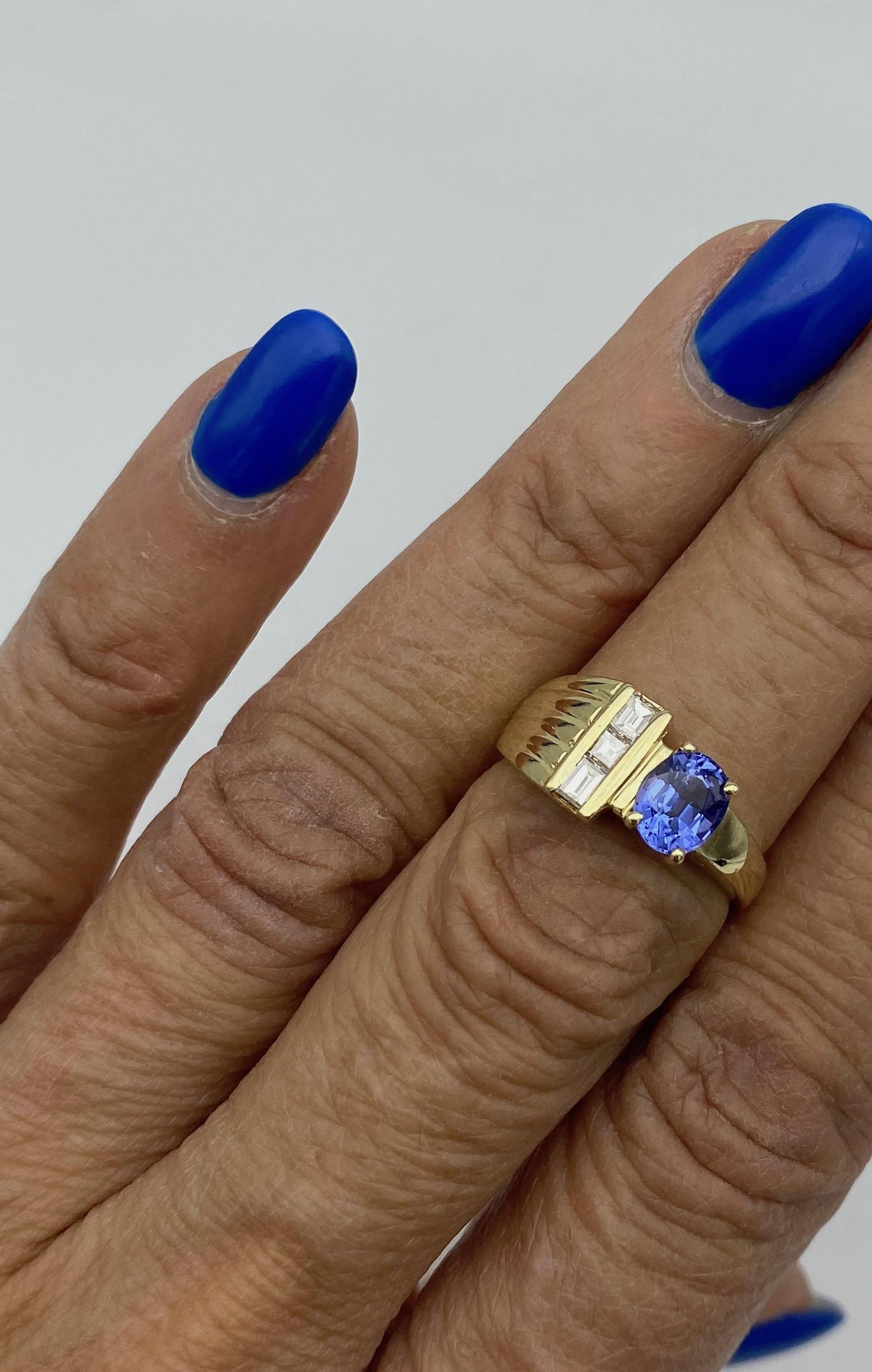 Tanzanite and Diamond Ring is a striking contemporary style set in 14 karat Yellow Gold.
The oval-shaped tanzanite measures 6.90 x 5.63 mm in diameter, weighing approximately 1.00 carat.
3- diamonds are channels set on the side of the ring. The cuts