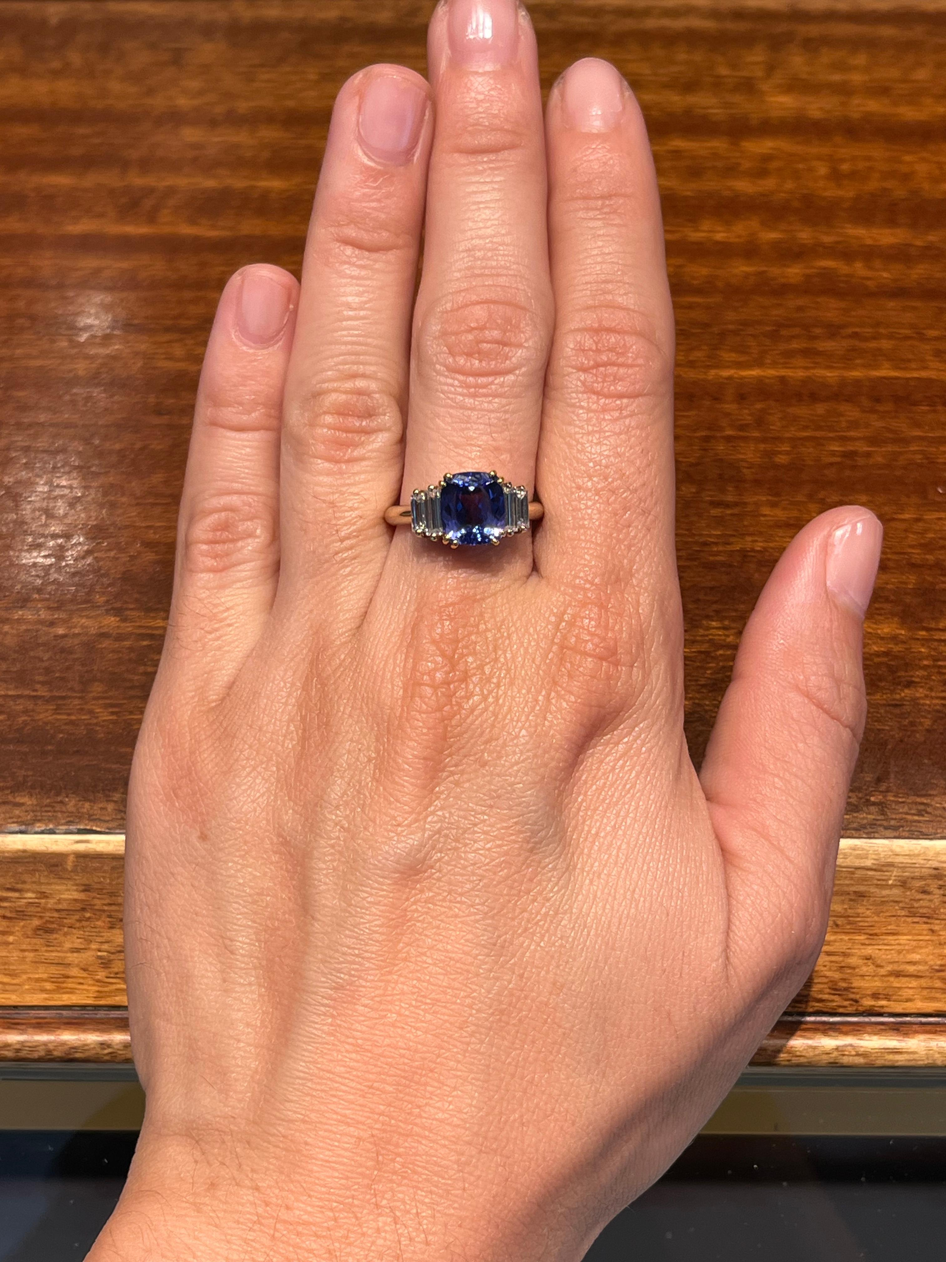 Un anello con tanzanite e diamante baguette realizzato da Bracken Jewellers a Los Angeles, California. Una tanzanite ricca e colorata, che emana colori blu e viola, è il centro di questo anello, completato da diamanti taglio baguette graduati su