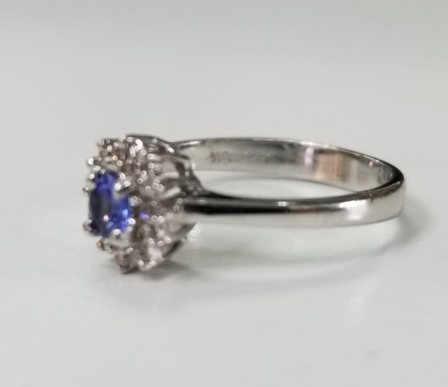 14k white gold Tanzanite and diamond cluster ring, containing 1 round tanzanite weighing .15pts. and 12 round full cut diamonds of very fine quality weighing .12pts.  This ring is a size 4.5 but we will size to fit for free.