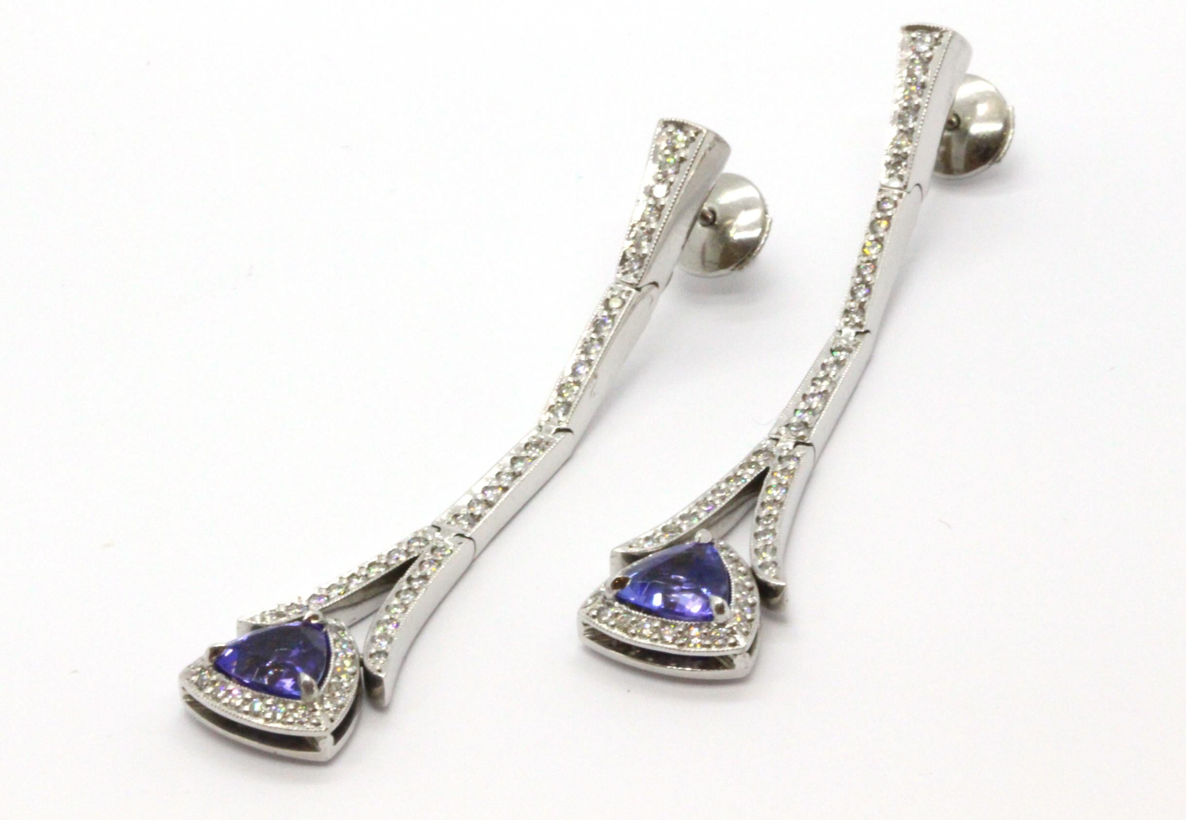 18ct White Gold Handcrafted Tanzanite and Diamond Drop Earrings.

Gemstone Details:
2 = 2.02ct Trilliant Cut Tanzanites
104 = 0.94ct Round Brilliant Cut Diamonds, Colour F/G, Clarity VS1

The Tanzanites are three claw set and are surrounded by a