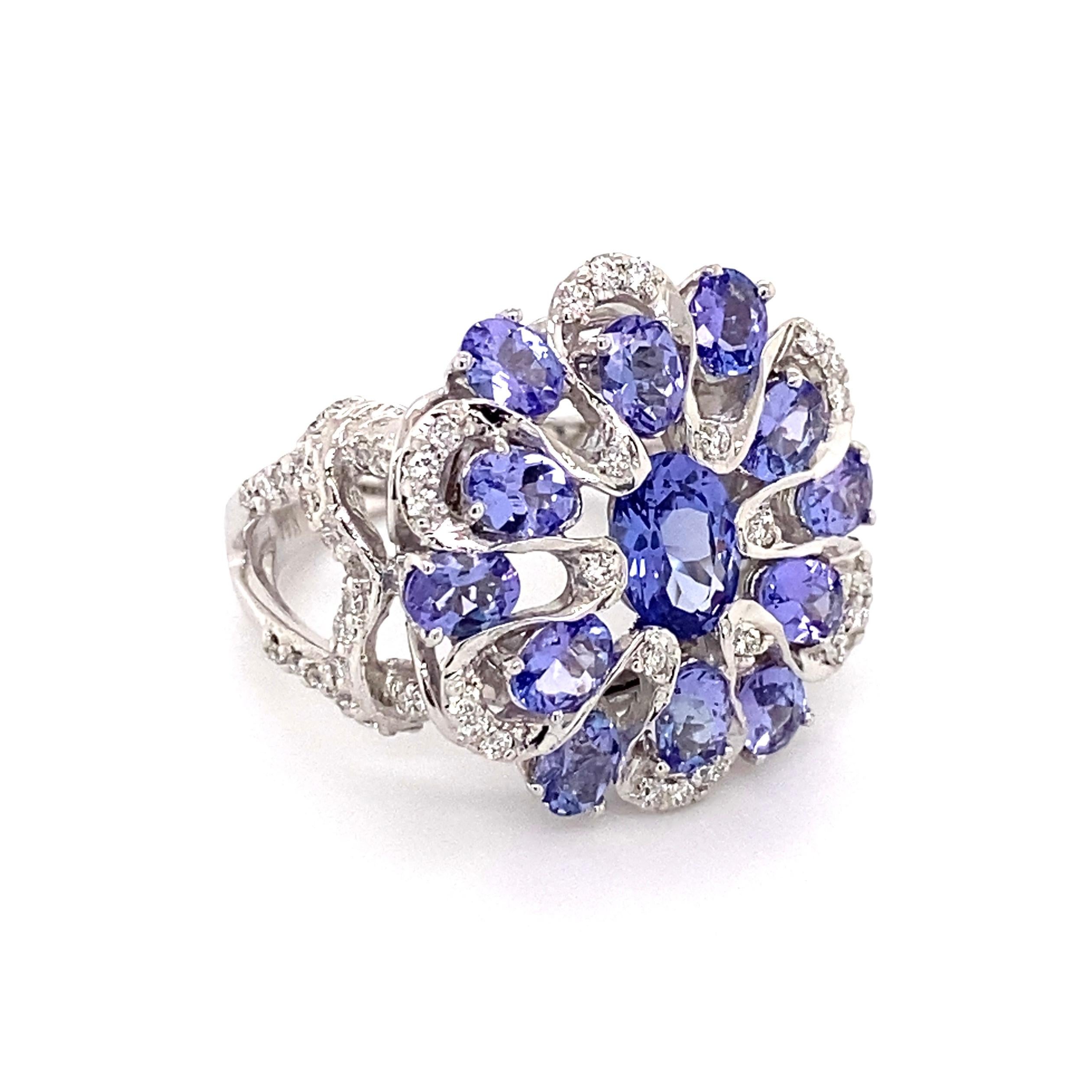 Simply Beautiful! Striking! and Finely detailed Tanzanite and Diamond Cocktail Ring. Center Hand set with an oval Tanzanite, artfully surrounded by Tanzanite and Diamonds. Measuring approx. 1.00” l x 0.84” w x 0.80” h. Hand crafted in 14 Karat White