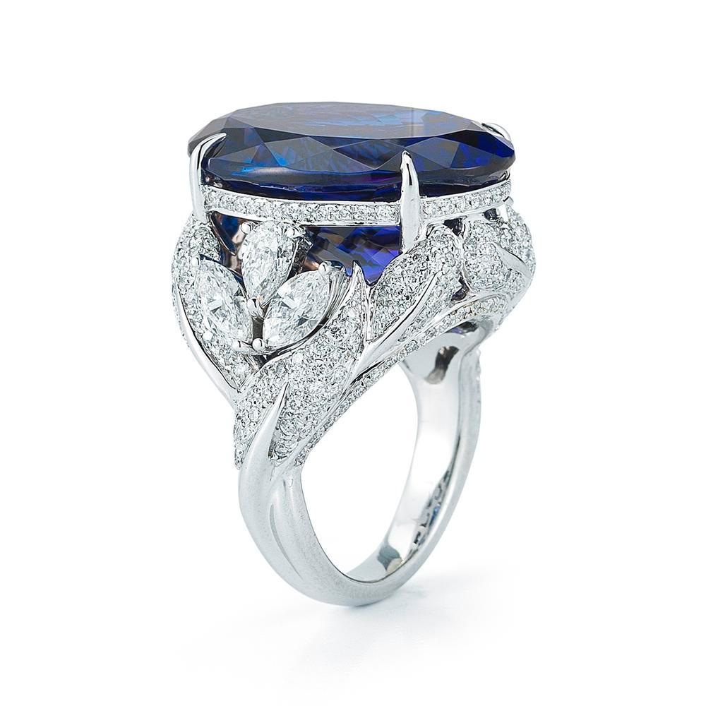 DAZZLING TANZANITE OVAL AND DIAMOND RING
Exquisitely hand-set diamond leaves climb the sides of this beautiful oval Tanzanite ring.
 
Item:	# 01800
Setting:	18K W
Lab:	GIA
Color Weight:	23.63 ct. of Tanzanite
Diamond Weight:	3.3 ct. of Diamonds
